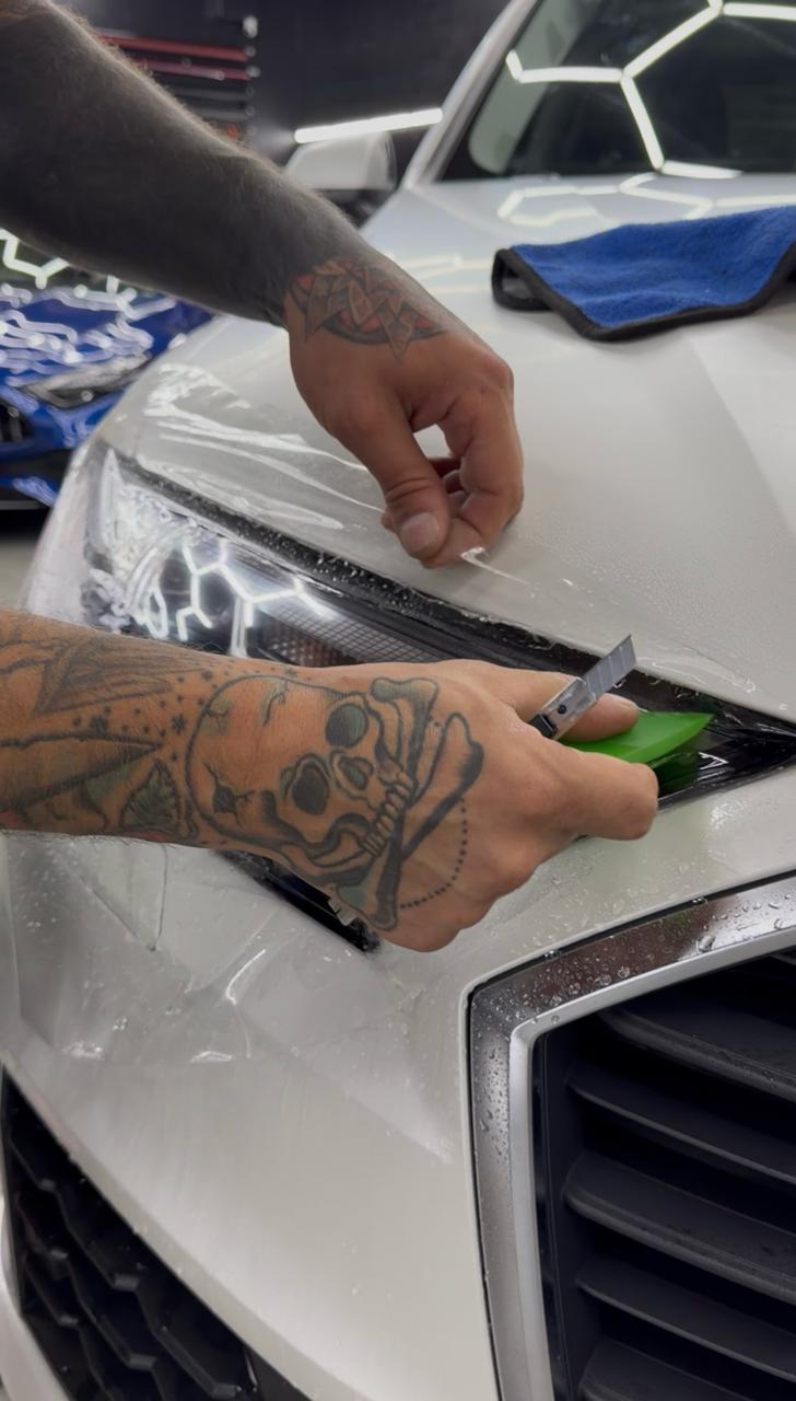 Close-up of a technician smoothing paint protection film with a squeegee