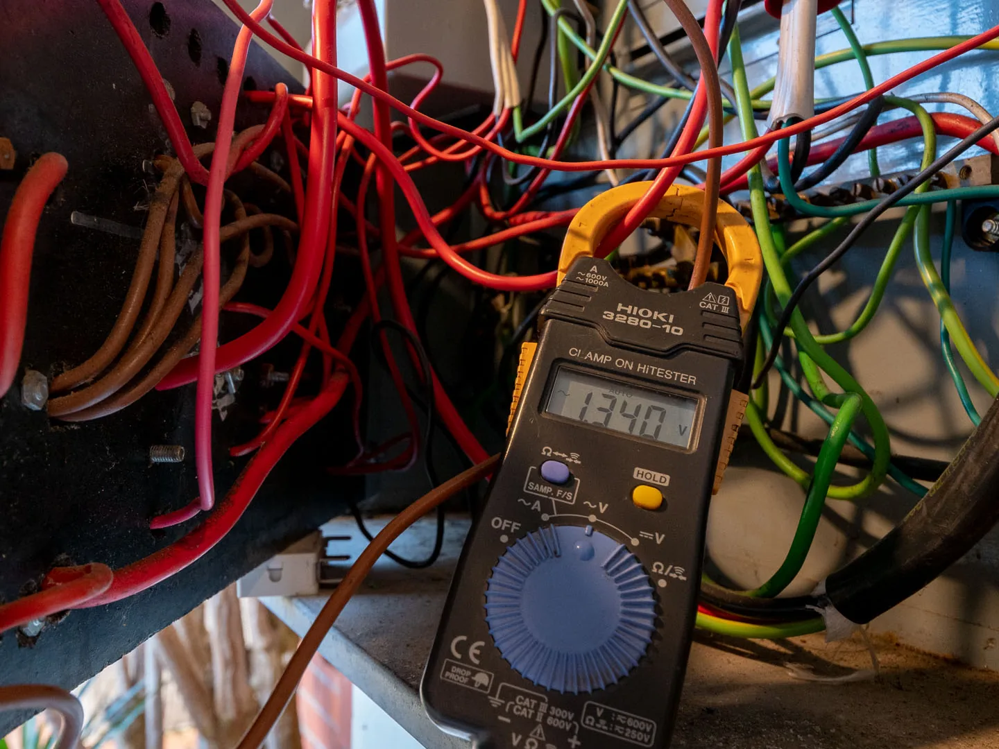 Clamp meter taking a reading among switchboard wiring