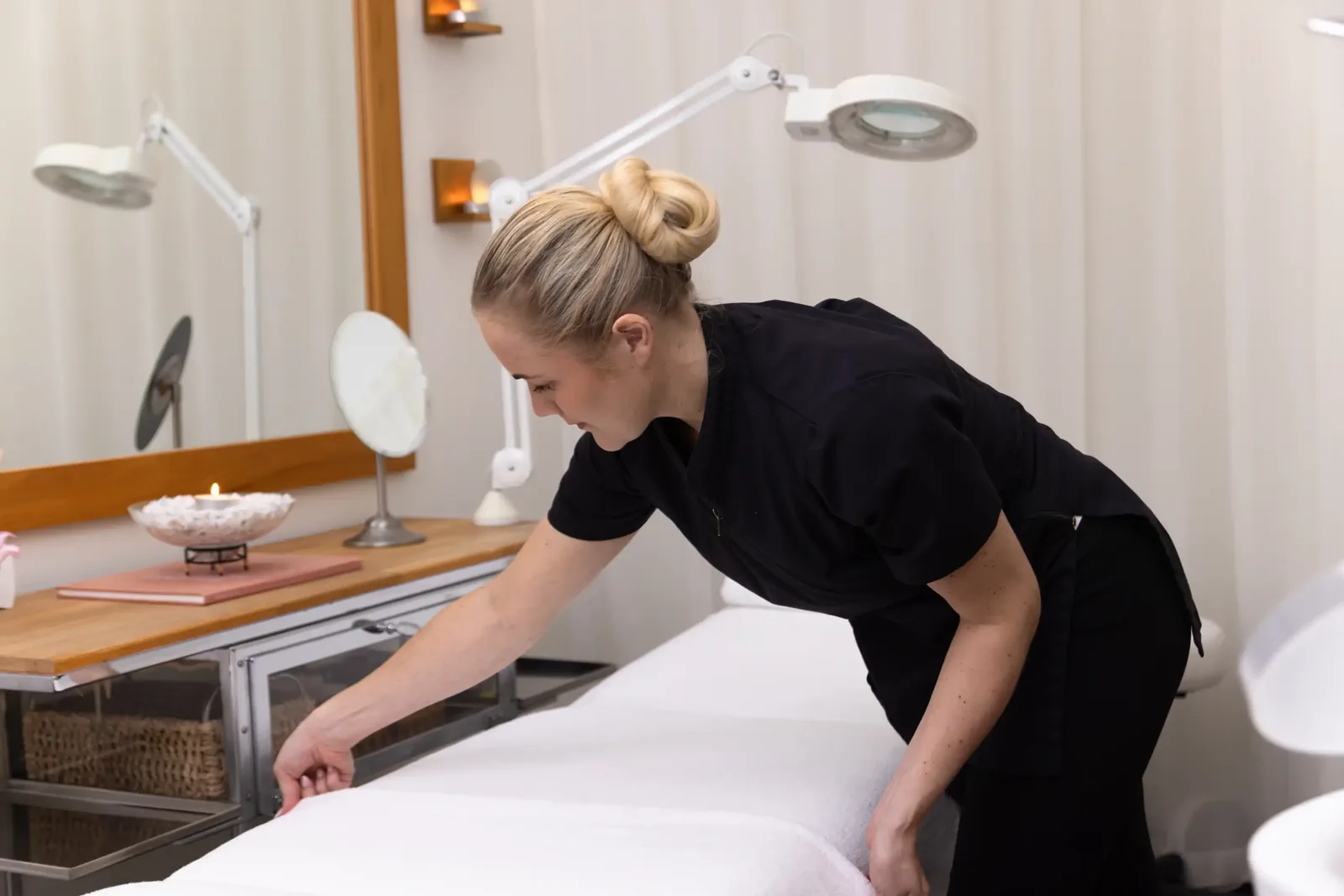 A male patient lying shirtless on a treatment bed wearing a disposable hair net, while a medical professional in a white lab coat and blue latex gloves applies a body sculpting device to his abdomen in a clinical setting.