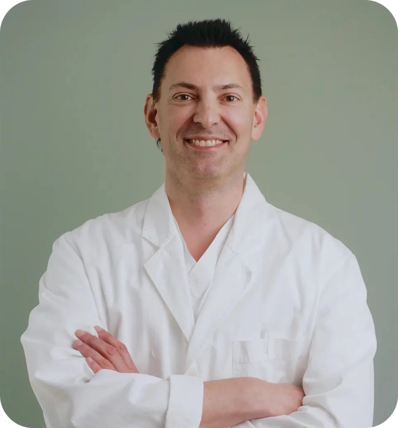 Dr. Zvonko Cogelja, a smiling man with short dark hair and light stubble, wearing a white medical lab coat with arms crossed, posed for a professional portrait photo.