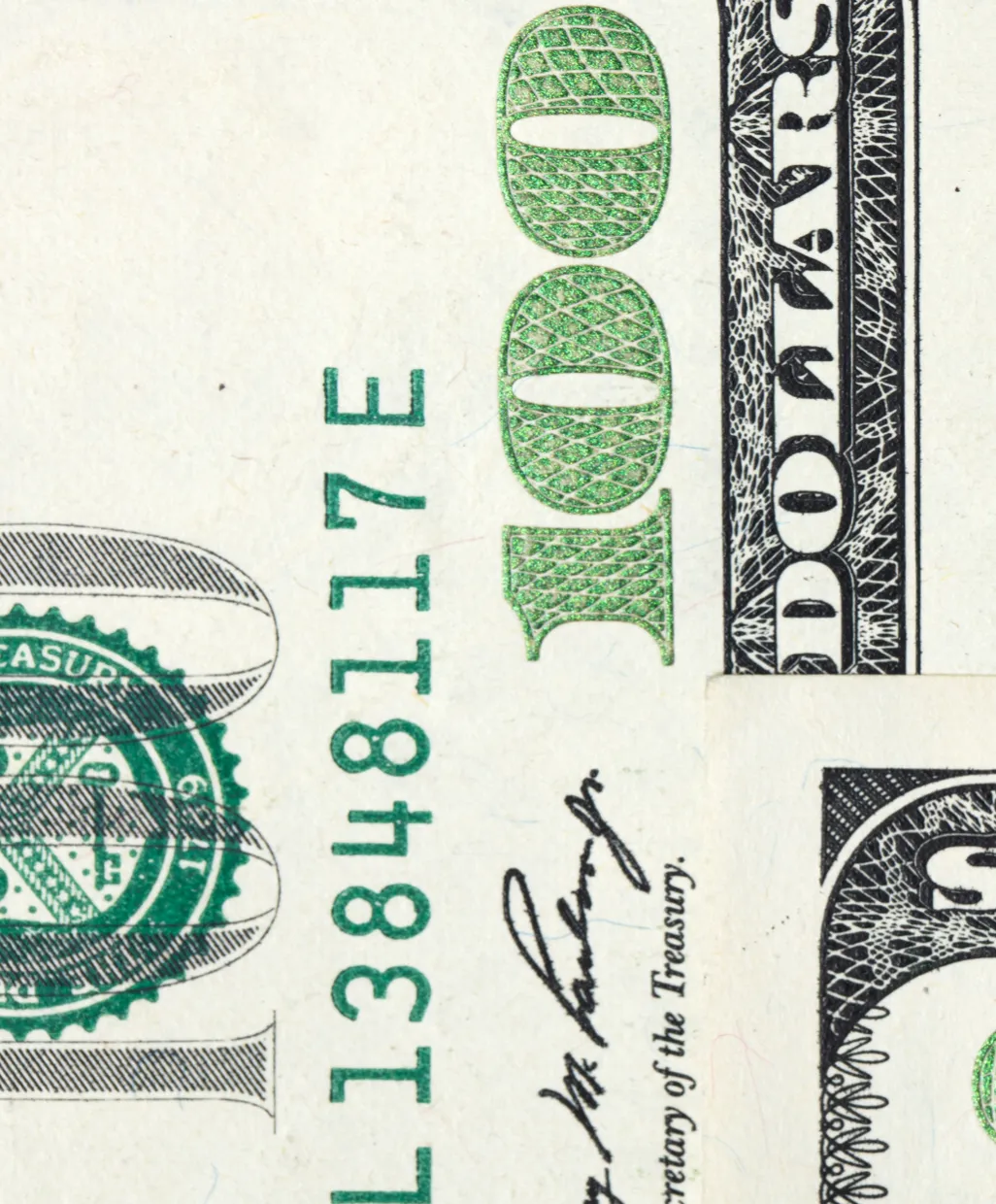 Close-up of a US $100 bill showing the number 100 and part of the Treasury seal and signature.