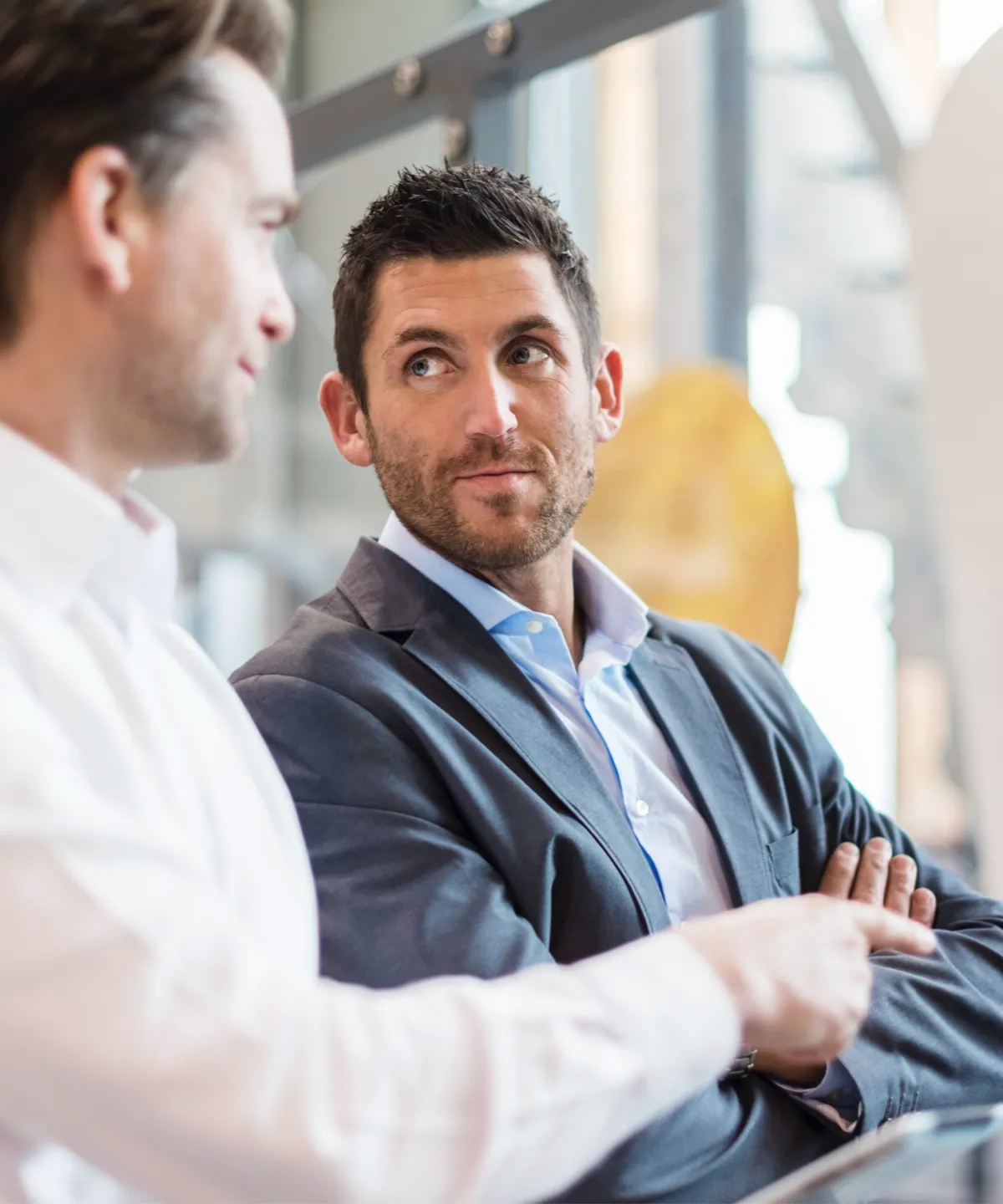 Two men in business attire engaging in a conversation in a modern office setting.