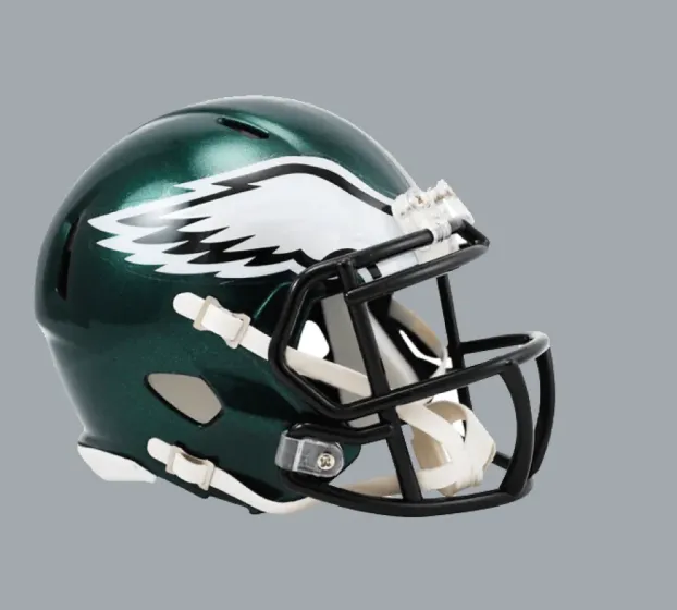 Green football helmet with white eagle wings logo and black faceguard on gray background.