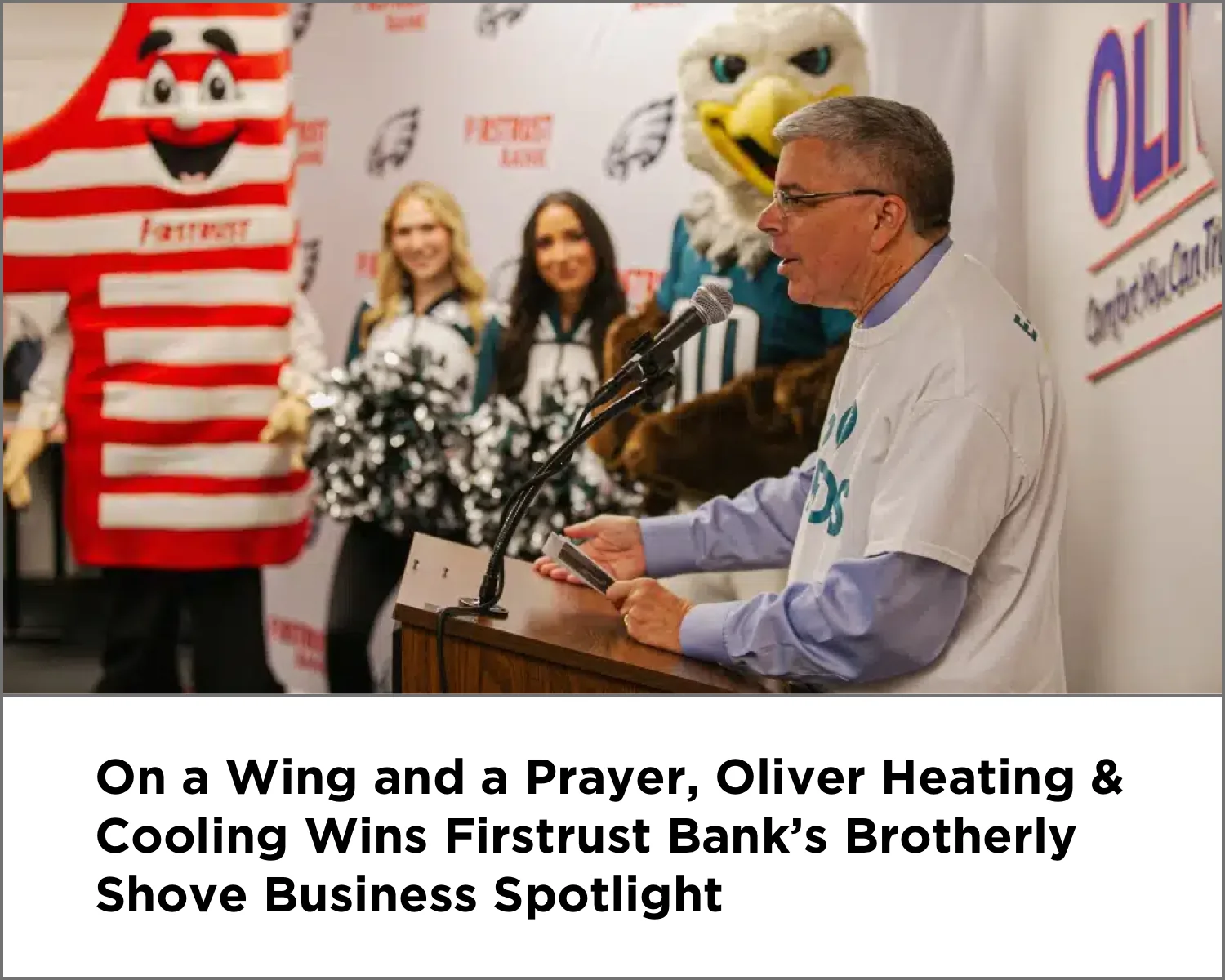 Man speaks at podium with cheerleaders and mascots behind him at a Firsttrust Bank event.