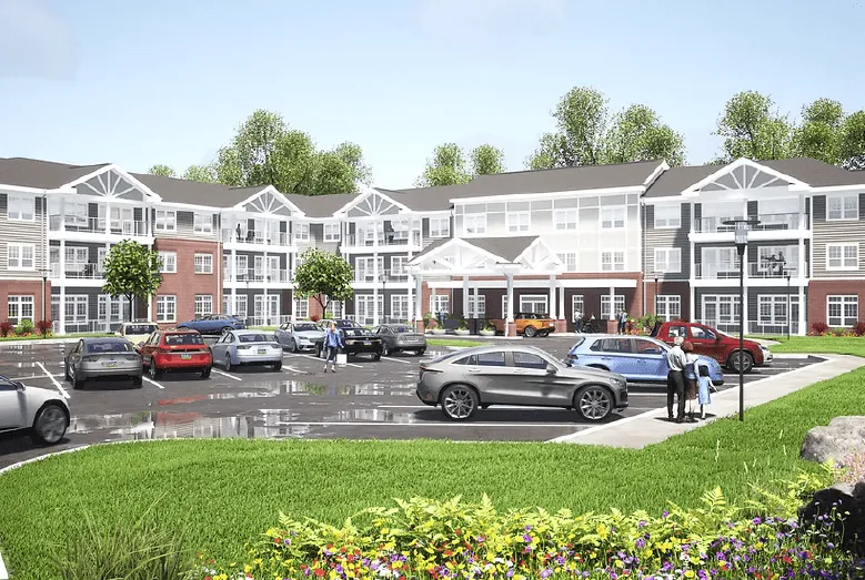 Three-story apartment building with front parking lot, green lawn, and people near the entrance.