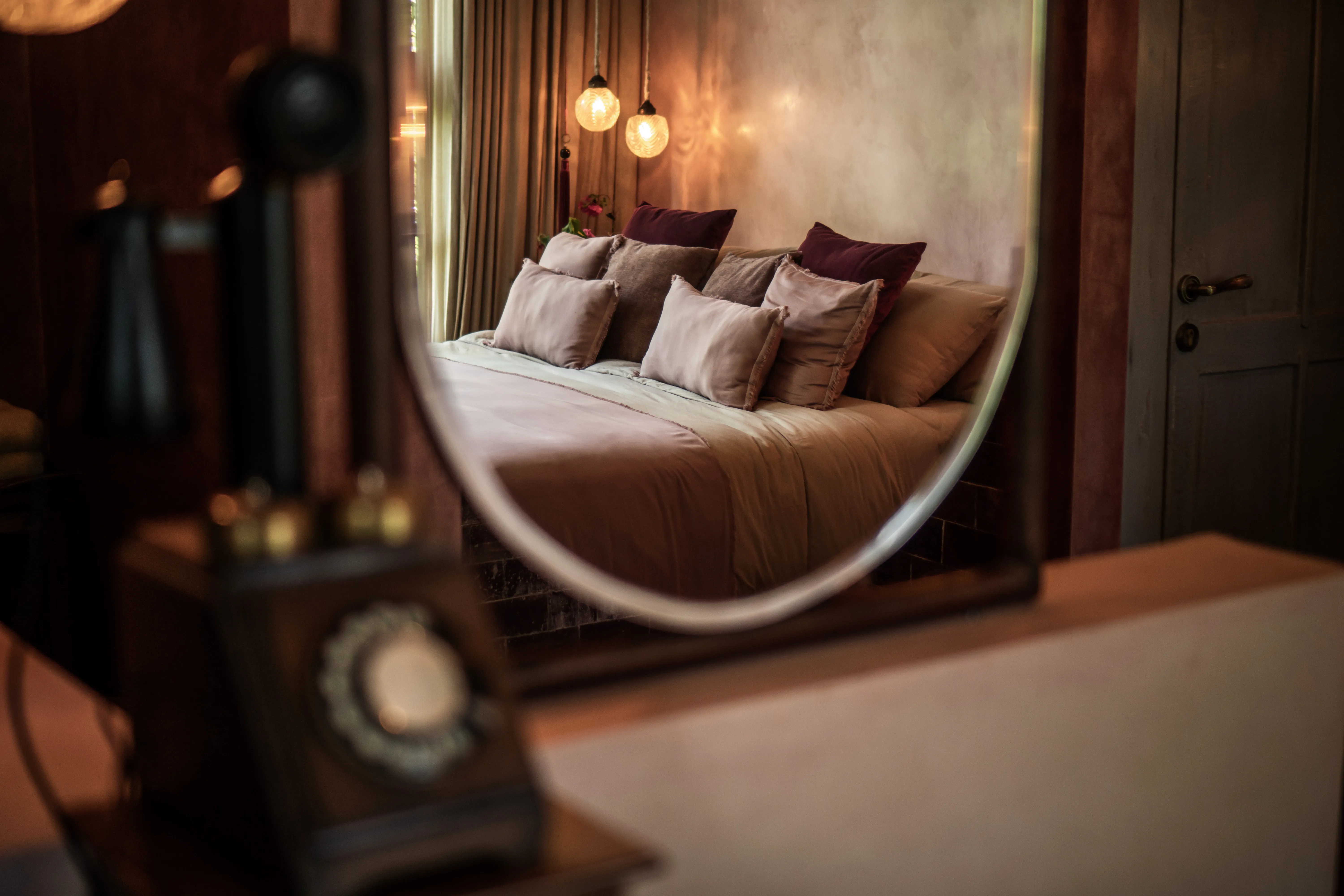 Reflection of a cozy king bed with plush pillows through a vintage vanity mirror at Balquisse Heritage Hotel