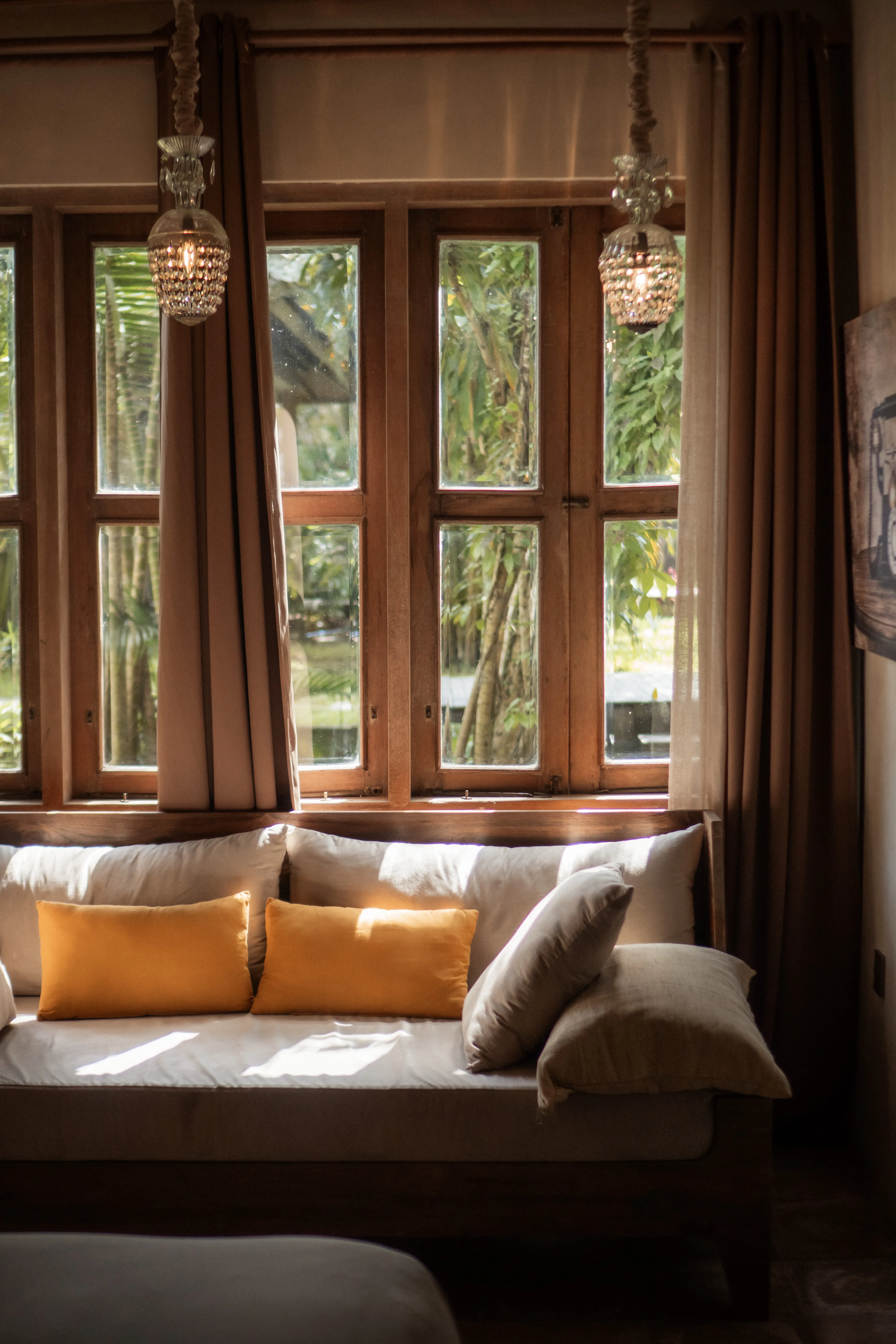 Sunlit daybed sofa with mustard yellow accent pillows in front of large wooden windows at Balquisse Heritage Hotel