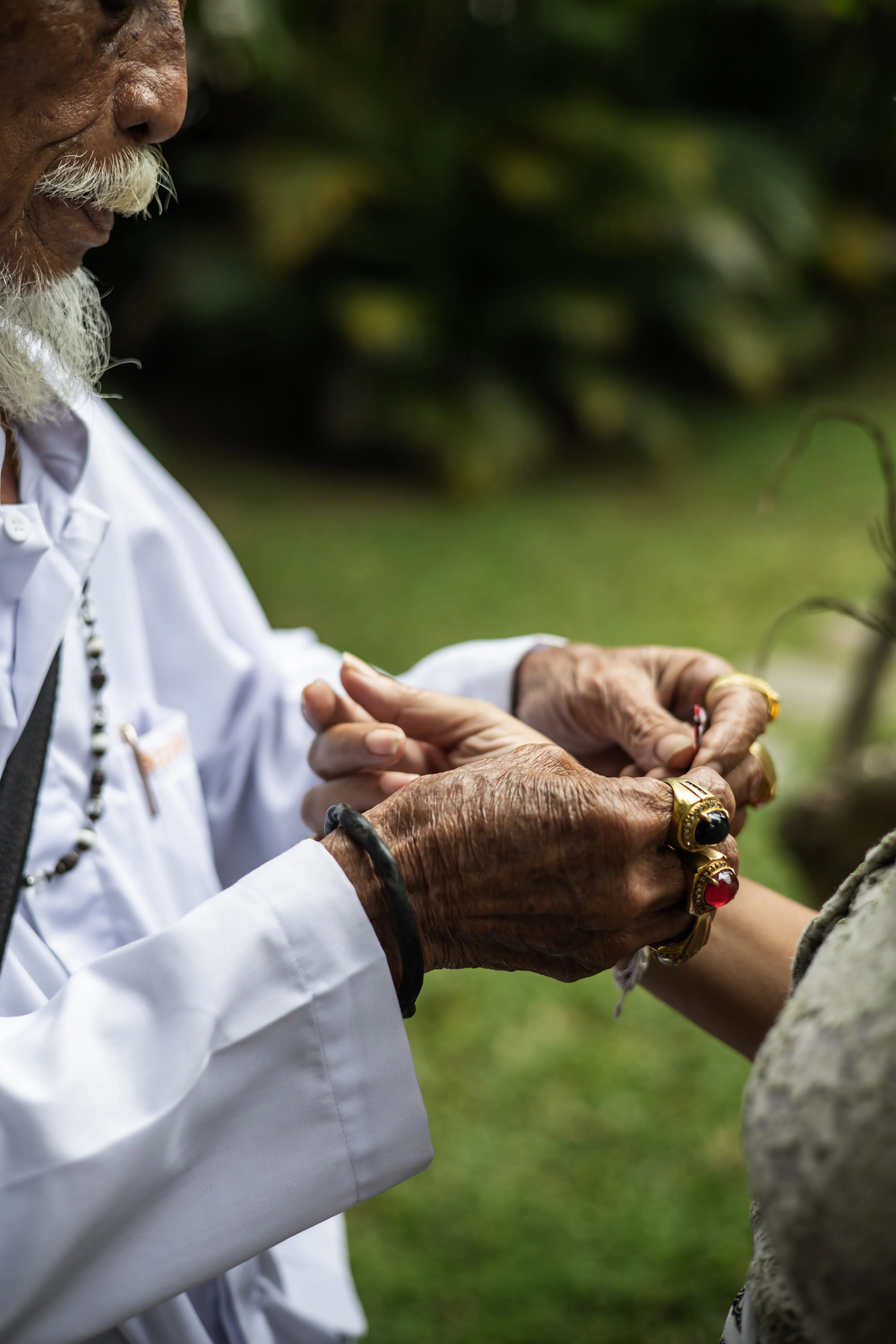 A traditional Balinese priest tying a sacred tridatu string during a spiritual blessing ceremony at the Campuhan retreat at Balquisse Heritage Hotel Jimbaran, Bali