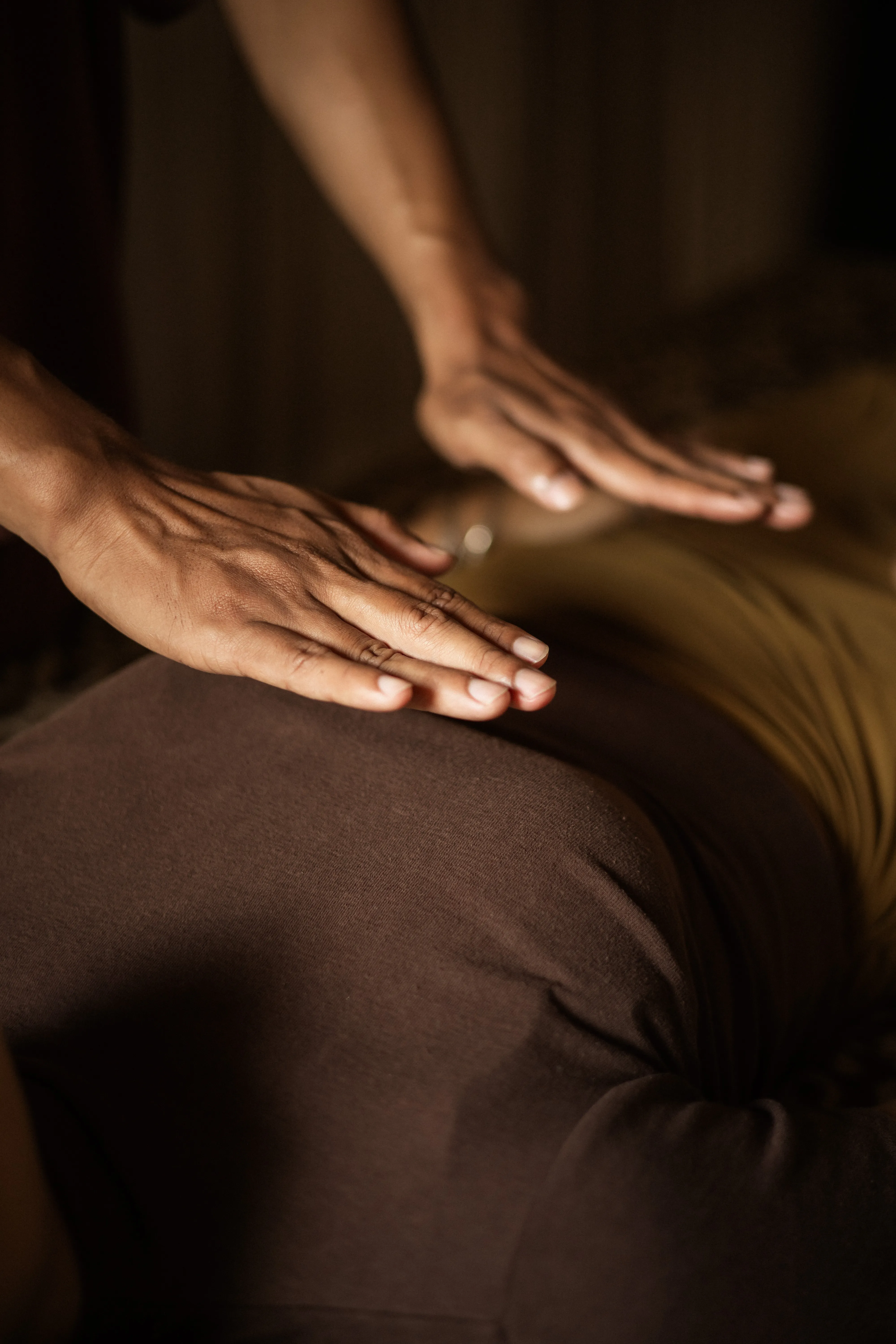 A therapist hovering hands over a client's back during an energy-balancing Reiki session.