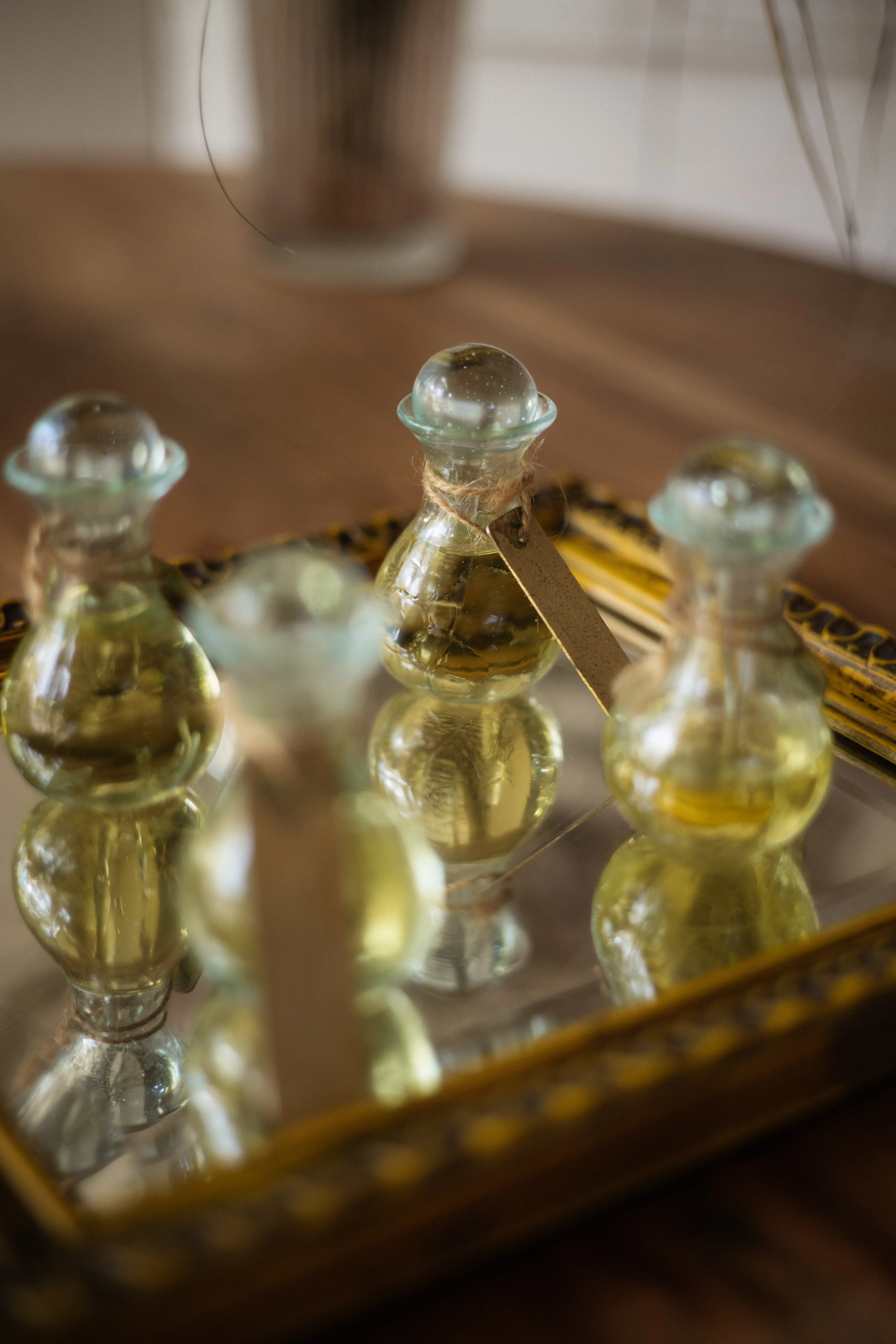Vintage glass bottles filled with natural massage essential oils arranged on a ornate mirror tray.