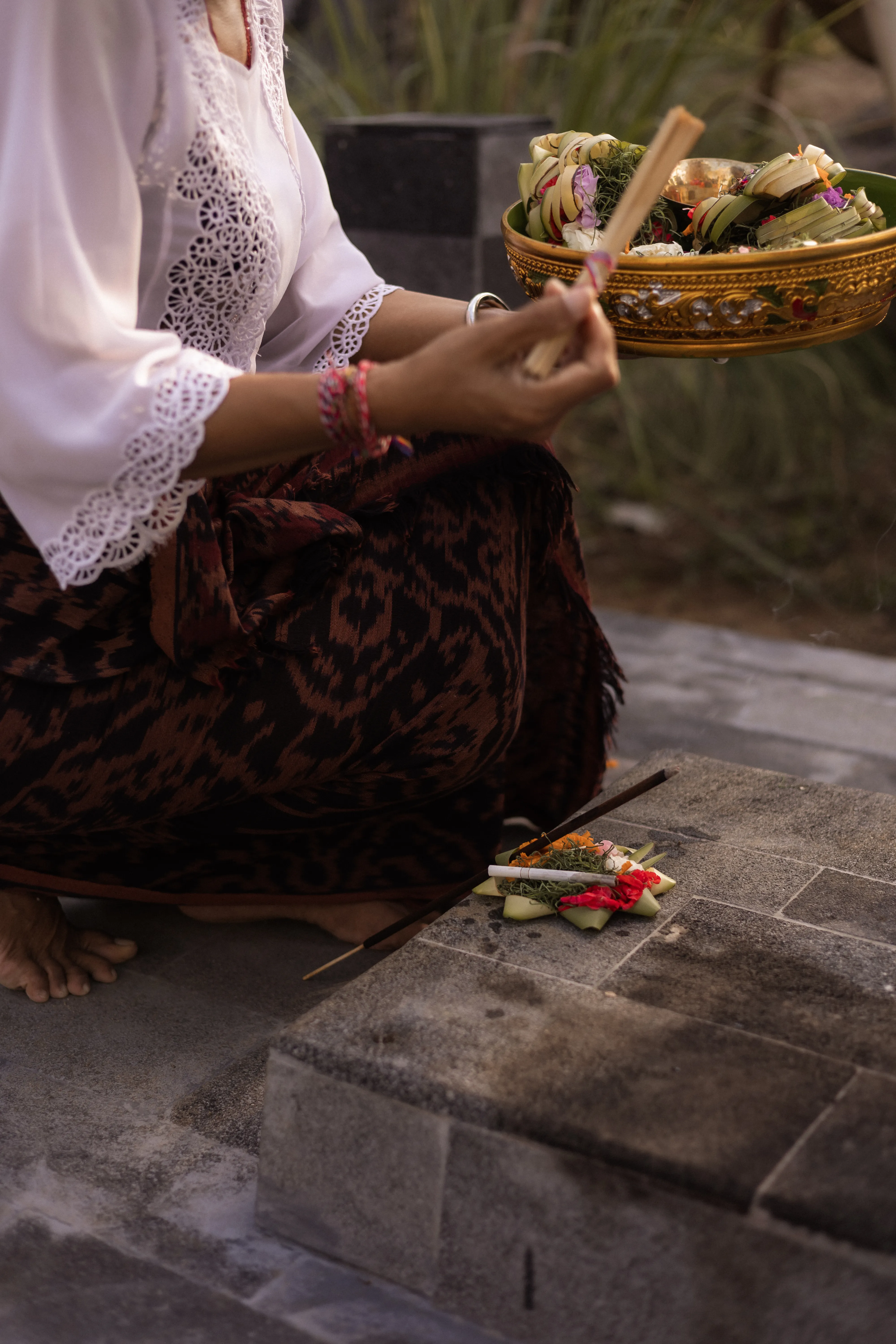Close-up of a Balinese spiritual healer holding incense and ceremonial offerings during a sacred ancestral blessing.