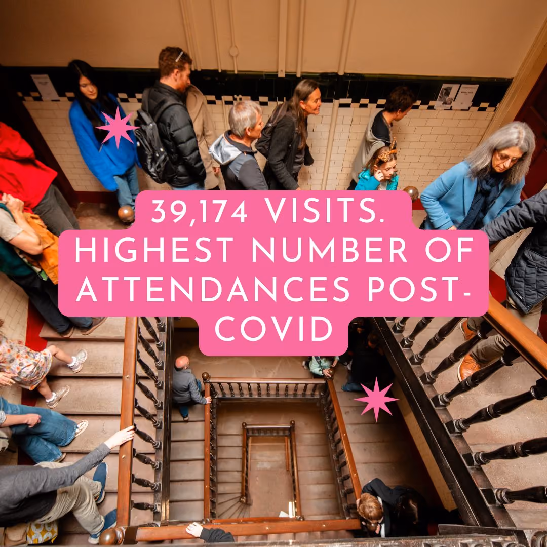 People attending an event inside a historic building, walking through a large staircase area.