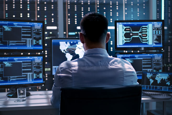 MJN engineer at work IT professional sitting at a desk with multiple monitors