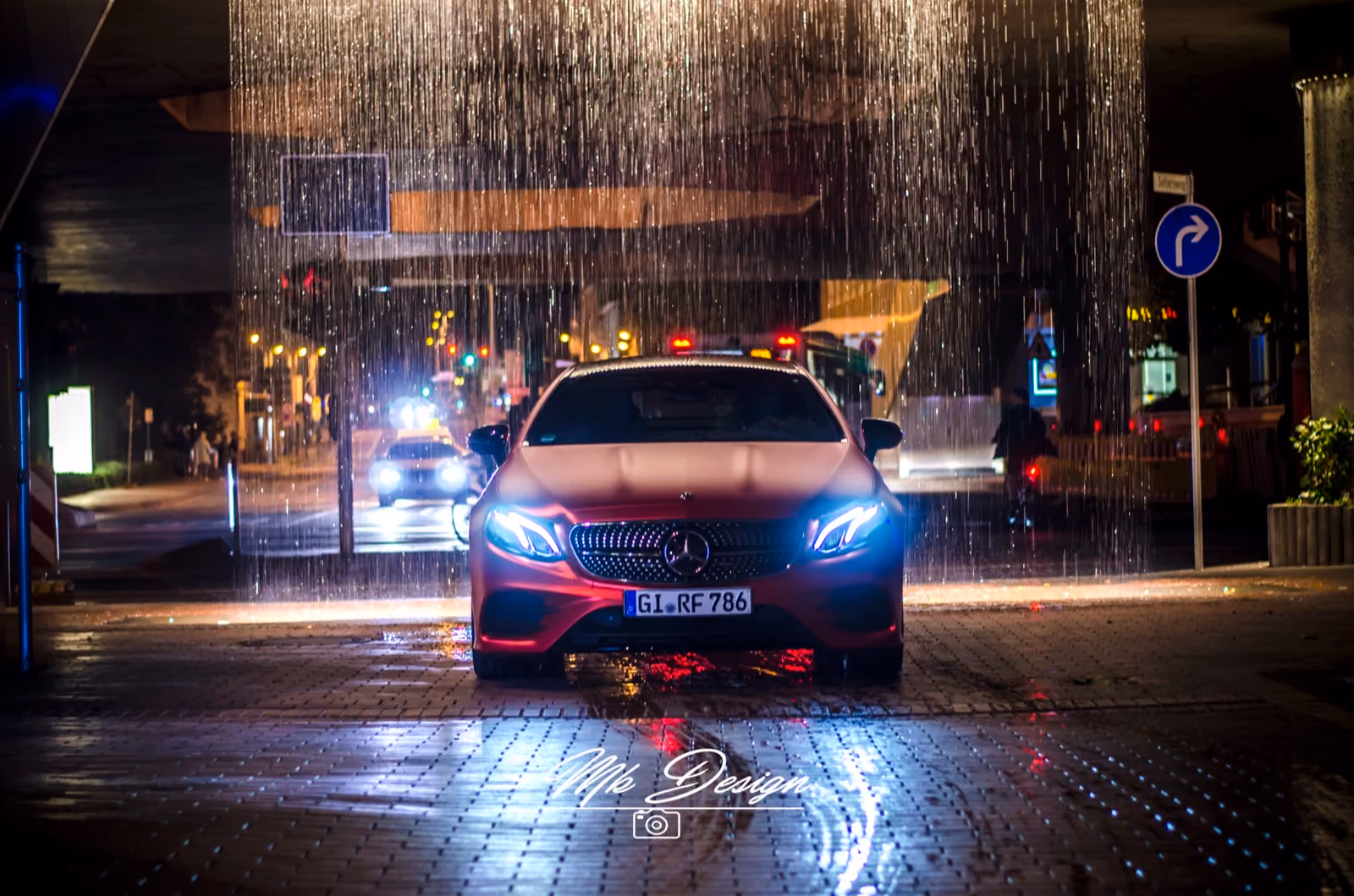 Mercedes E-Klasse Coupé in Mattrot foliert bei Nacht vor beleuchtetem Wasserspiel, Frontansicht