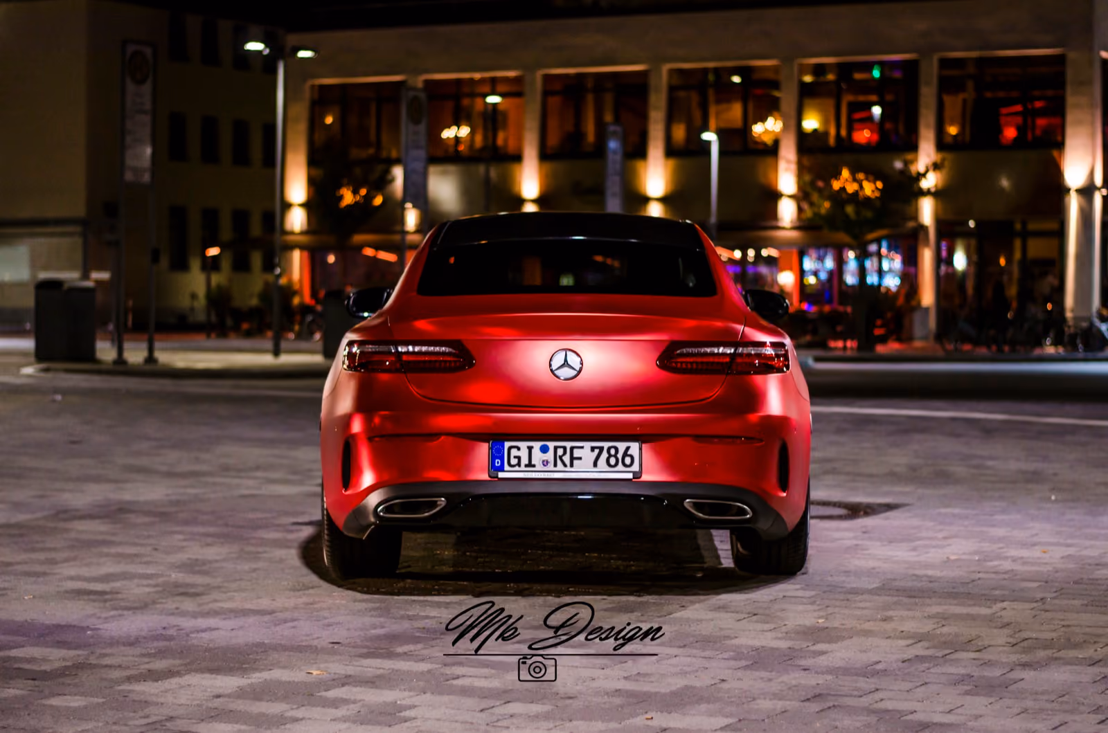 Heckansicht eines mattrot folierten Mercedes E-Klasse Coupés bei Nacht in der Stadt