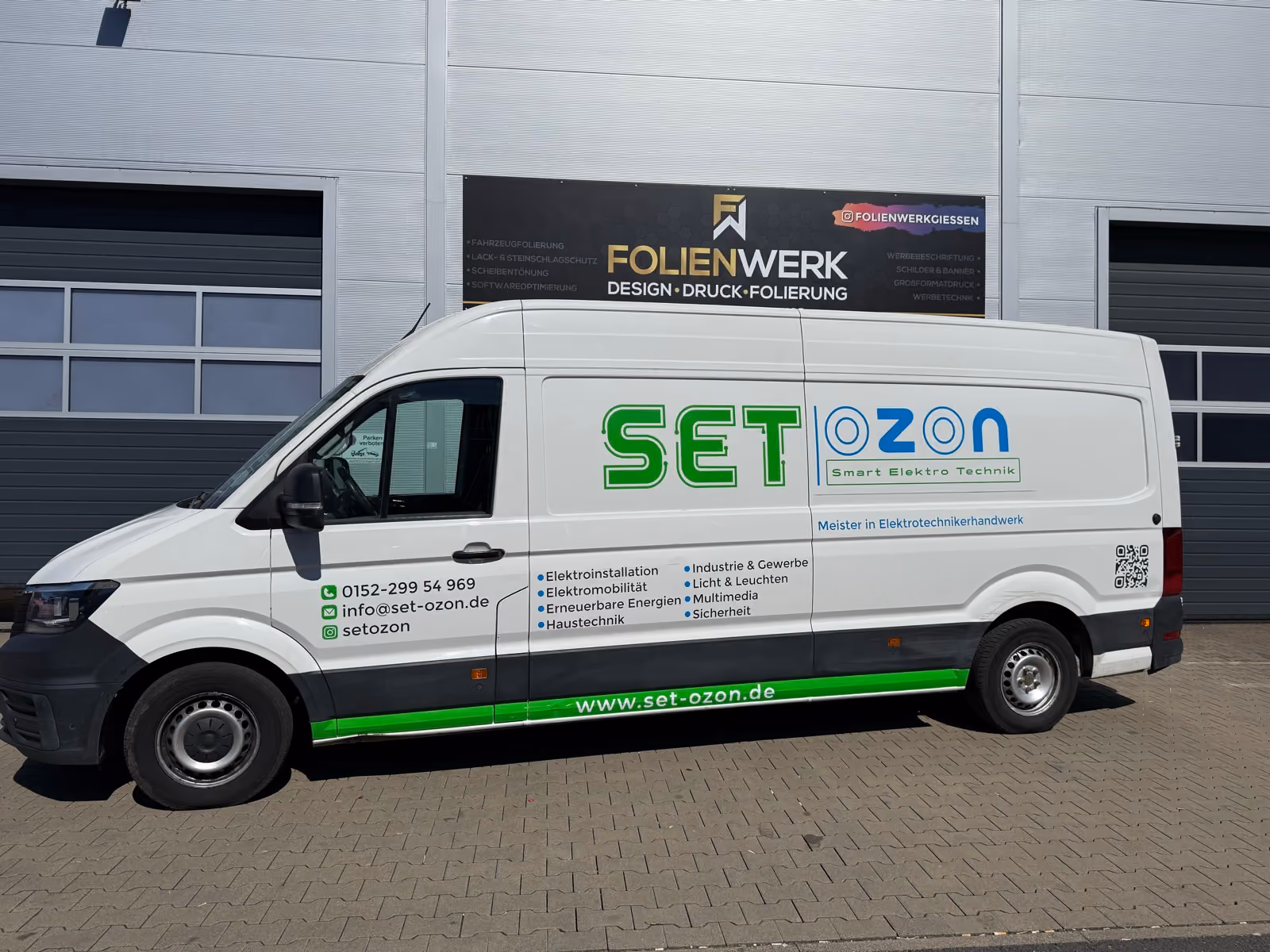 Weißer VW Crafter Kastenwagen mit Werbefolierung eines Elektrotechnik-Betriebs vor dem Folienwerk Gießen