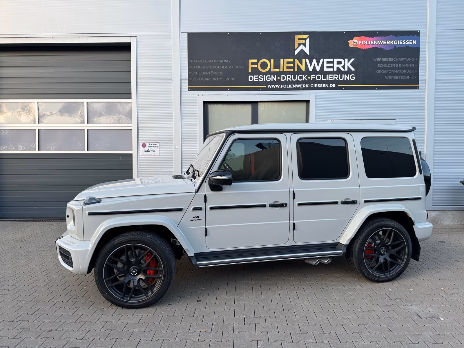 Weißer Mercedes-AMG G63 mit schwarzen Felgen vor dem Folienwerk Gießen