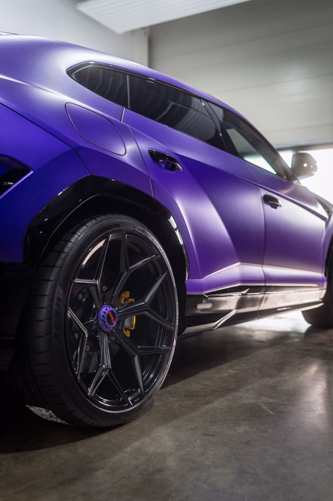 Heckpartie eines mattviolett folierten Lamborghini Urus in der Werkstatt, Detailaufnahme