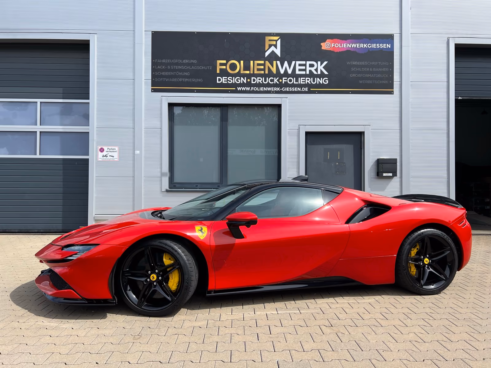 Roter Ferrari SF90 mit schwarz foliertem Dach vor dem Folienwerk Gießen