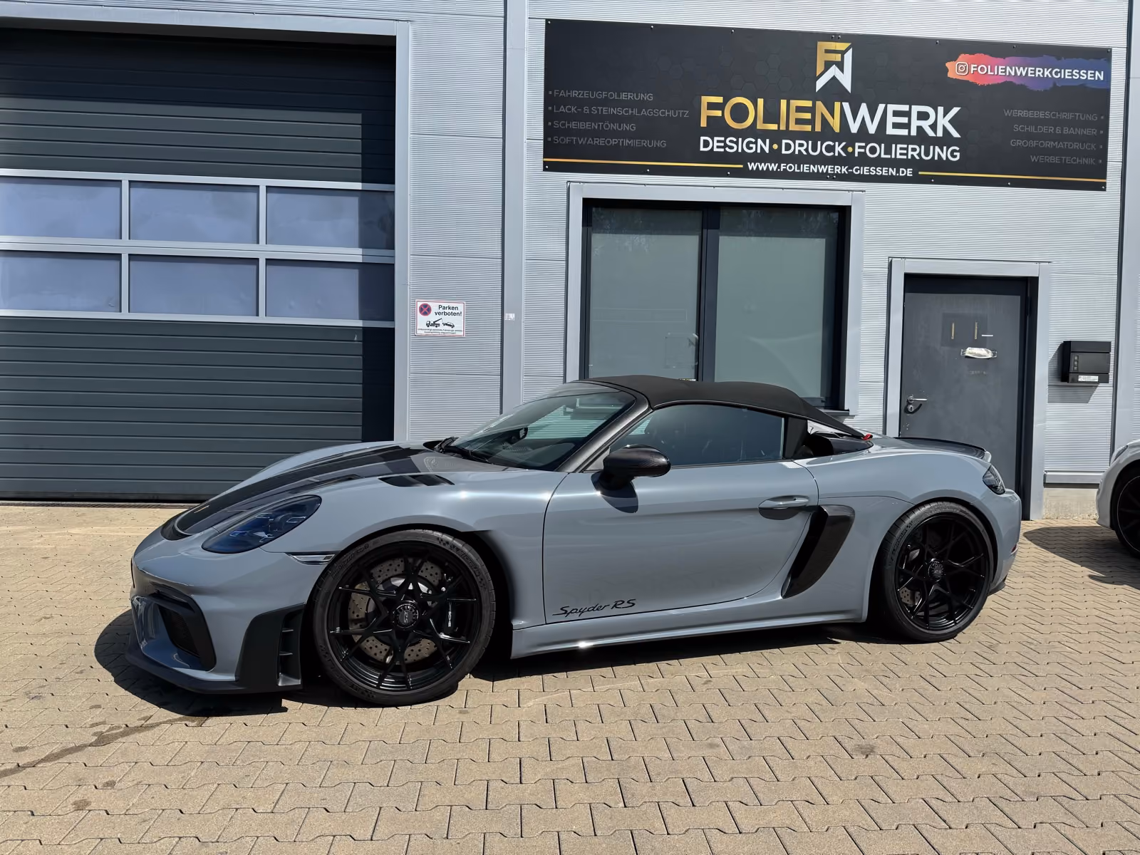 Porsche 718 Spyder RS in Grau mit schwarzem Verdeck, Seitenansicht vor dem Folienwerk Gießen