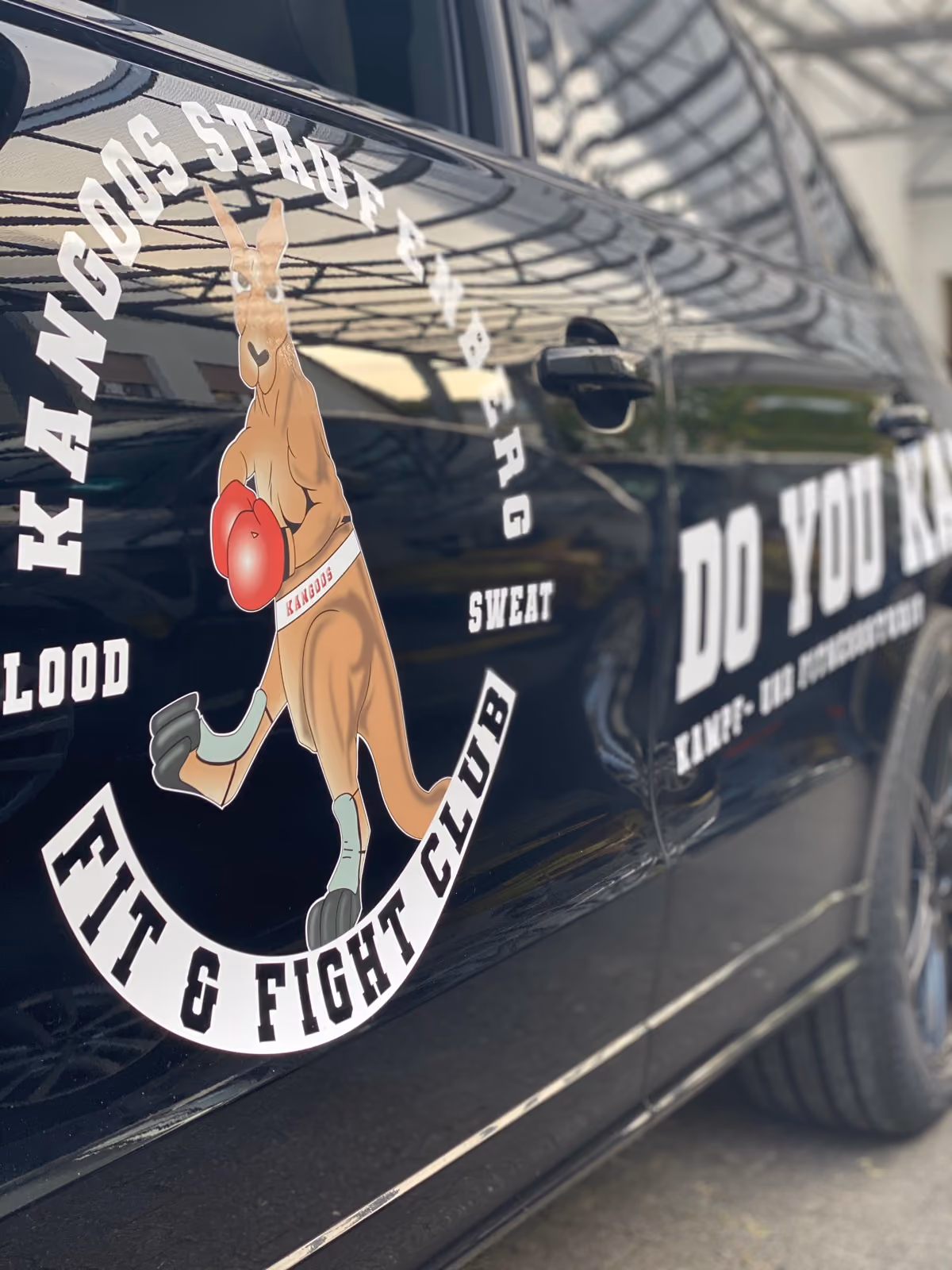 Detailaufnahme einer Werbefolierung mit Känguru-Logo eines Fit-und-Fight-Clubs auf schwarzem Van