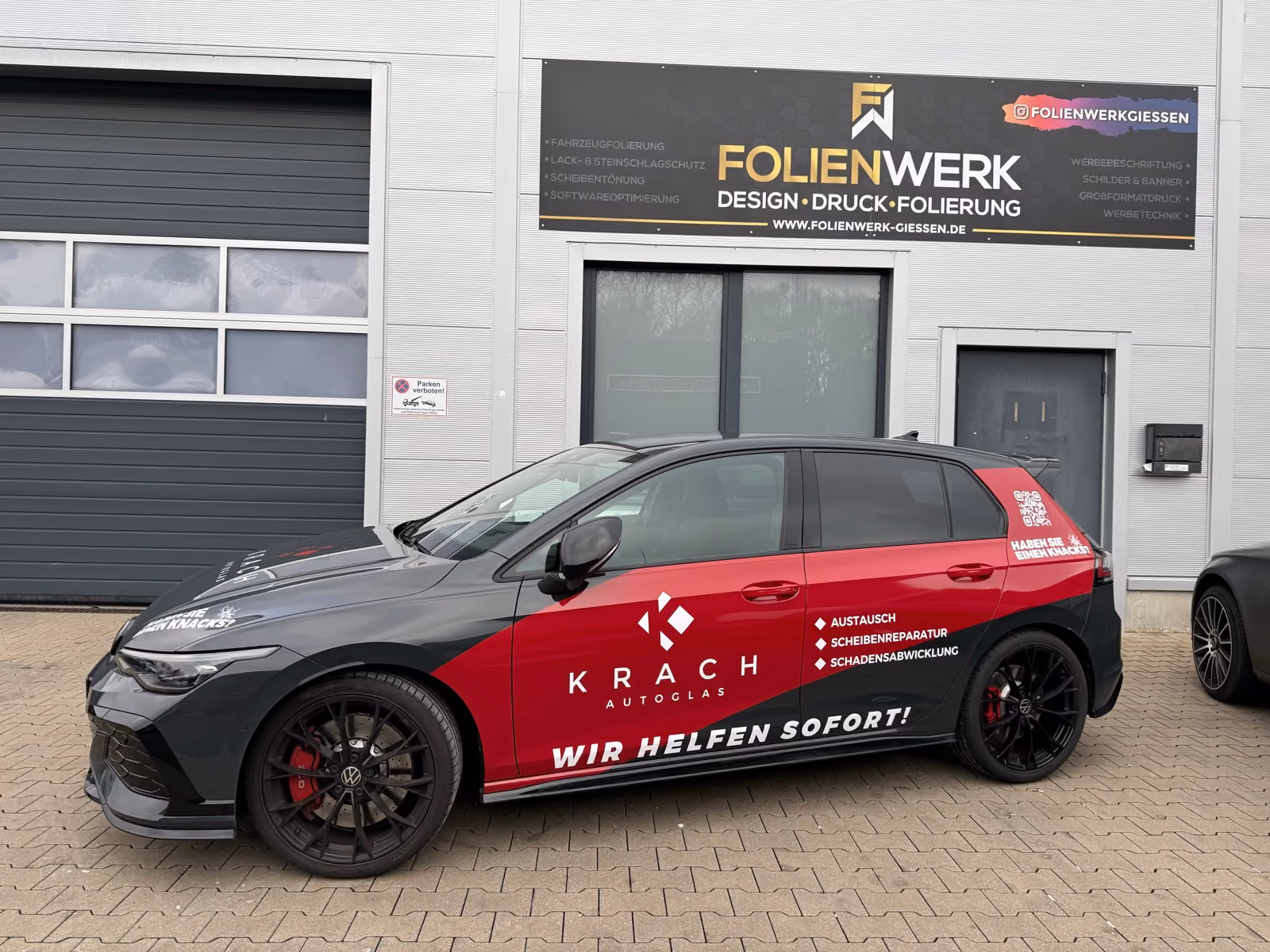 VW Golf in Schwarz-Rot mit Werbefolierung eines Autoglas-Betriebs vor dem Folienwerk Gießen