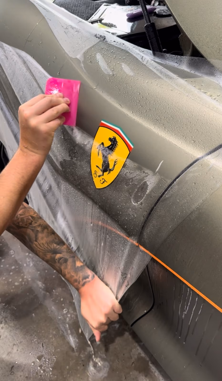 Detailaufnahme: Montage transparenter Lackschutzfolie (PPF) mit Rakel am Kotflügel eines Ferrari