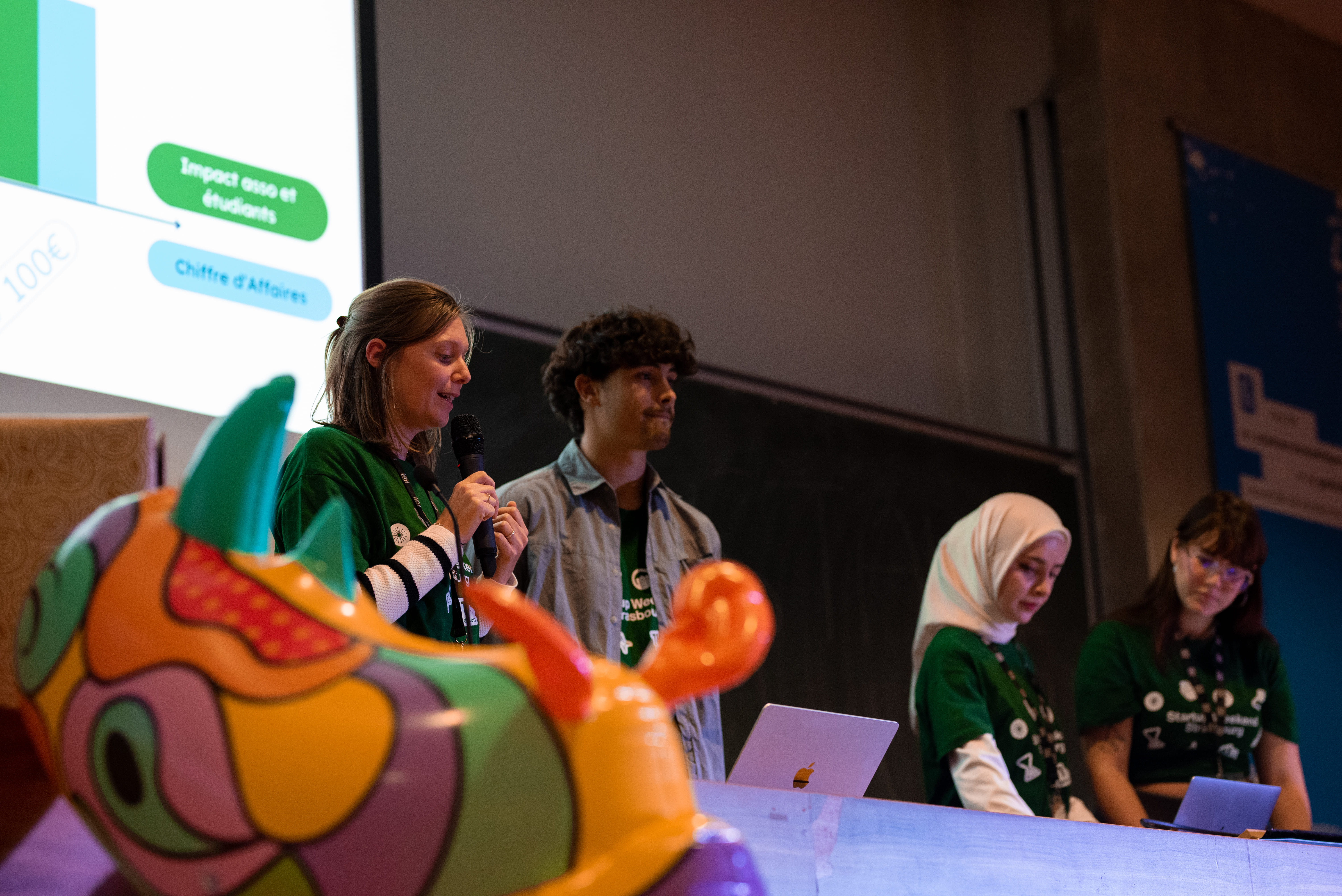 Quatre jeunes présentent devant un écran avec un graphique lors d'un événement ou atelier.