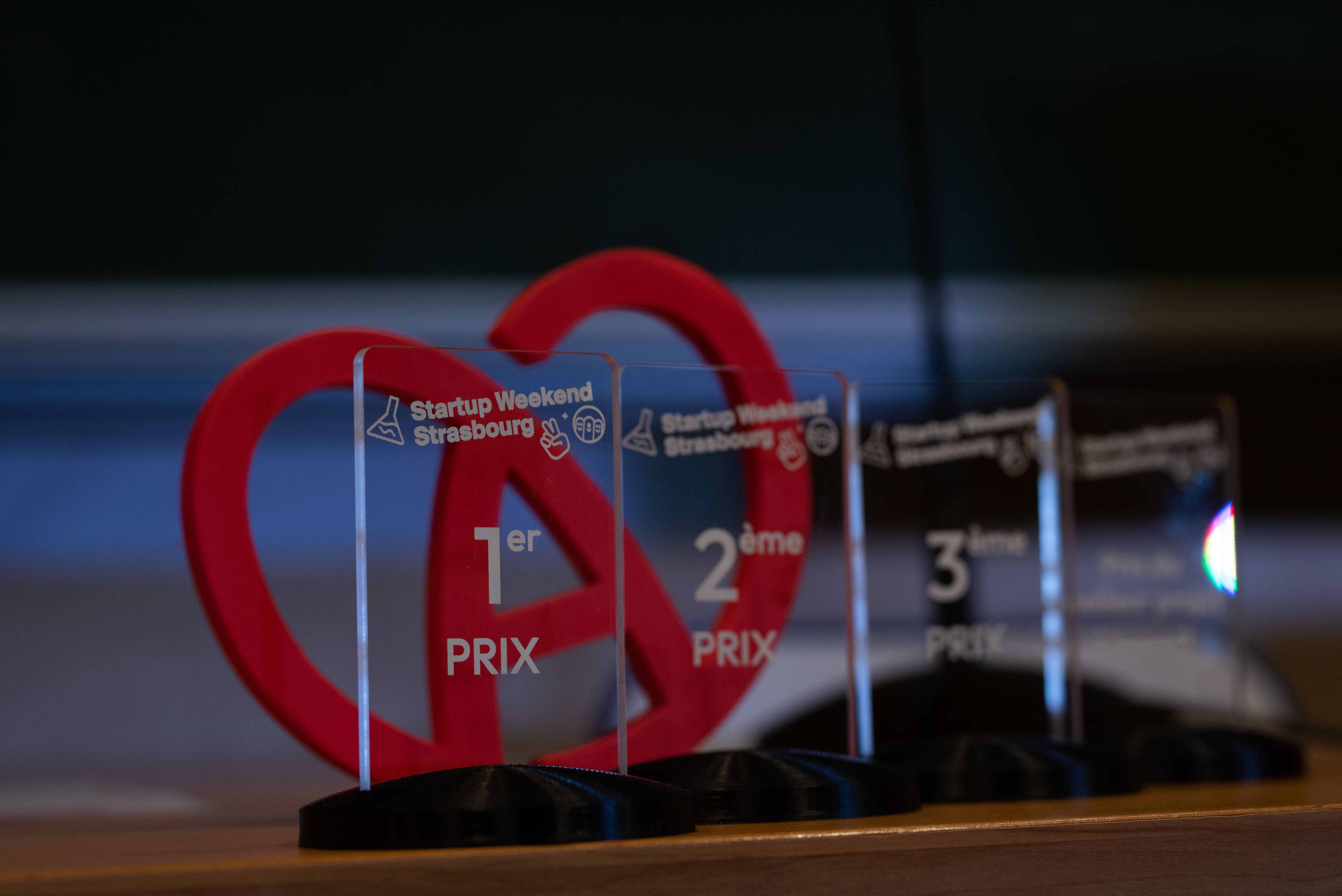 Trophées du Startup Weekend Strasbourg pour 1er, 2ème et 3ème prix alignés sur une table.