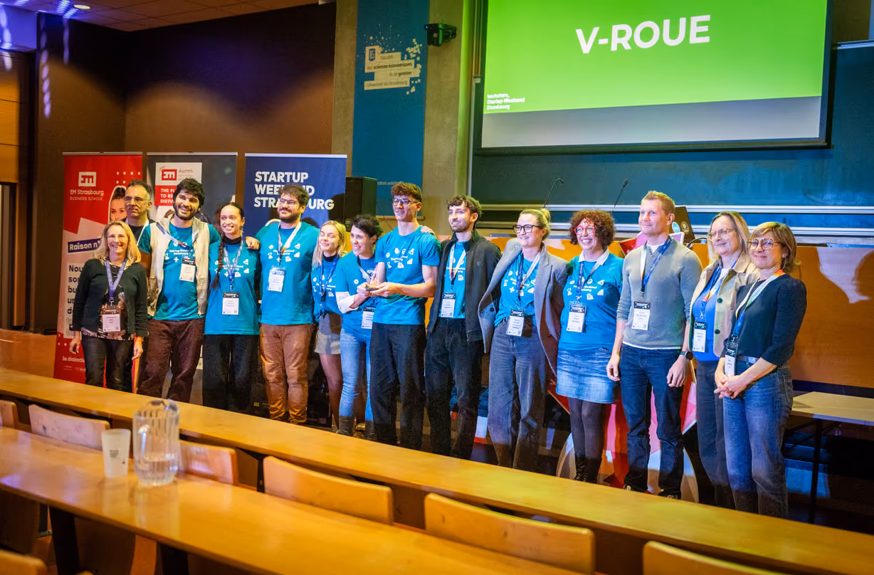 Groupe de dix personnes souriantes posant sur une scène lors d'un événement Startup Weekend Strasbourg.