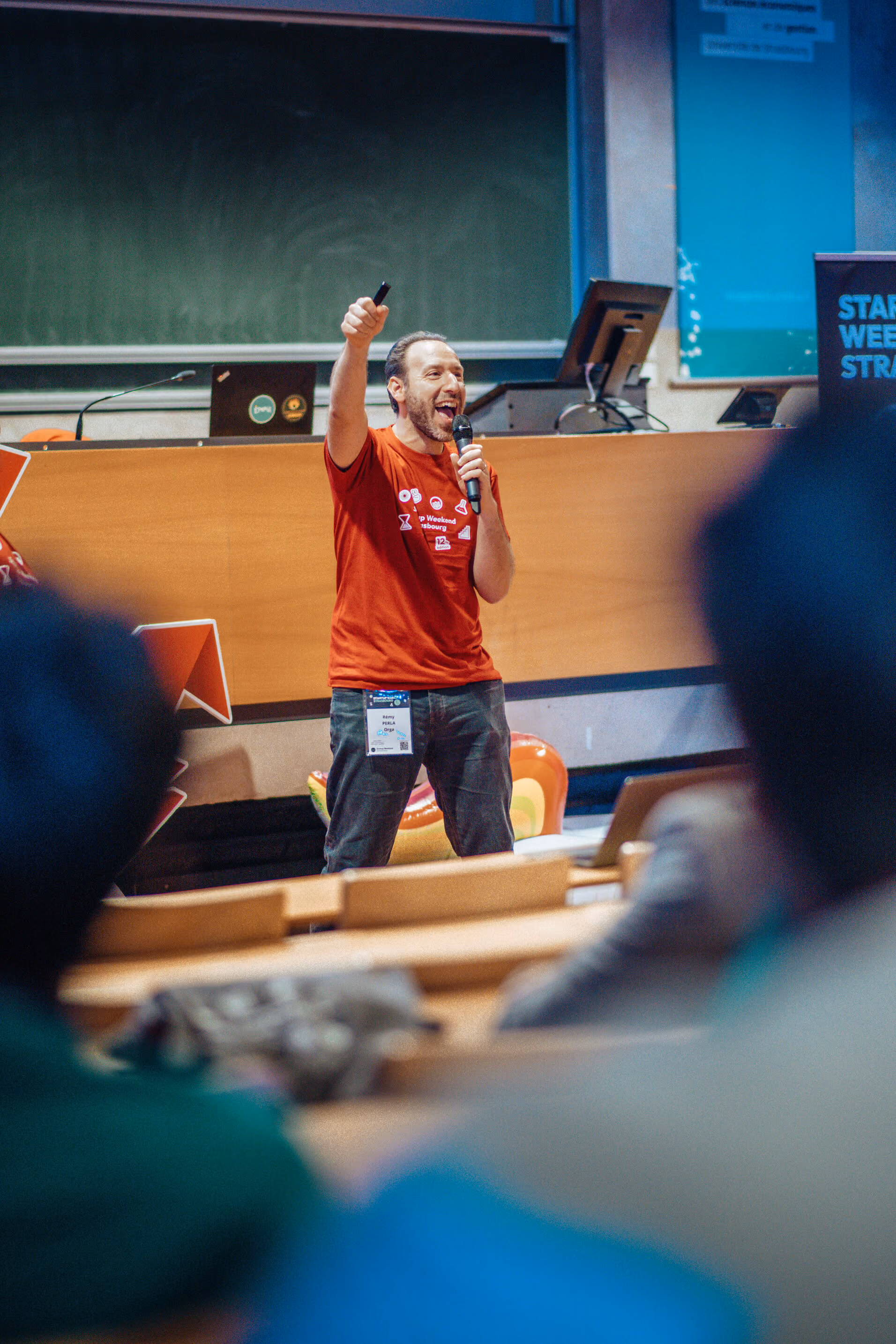Des personnes assises souriantes et applaudissant lors d'un événement dans une salle de conférence.