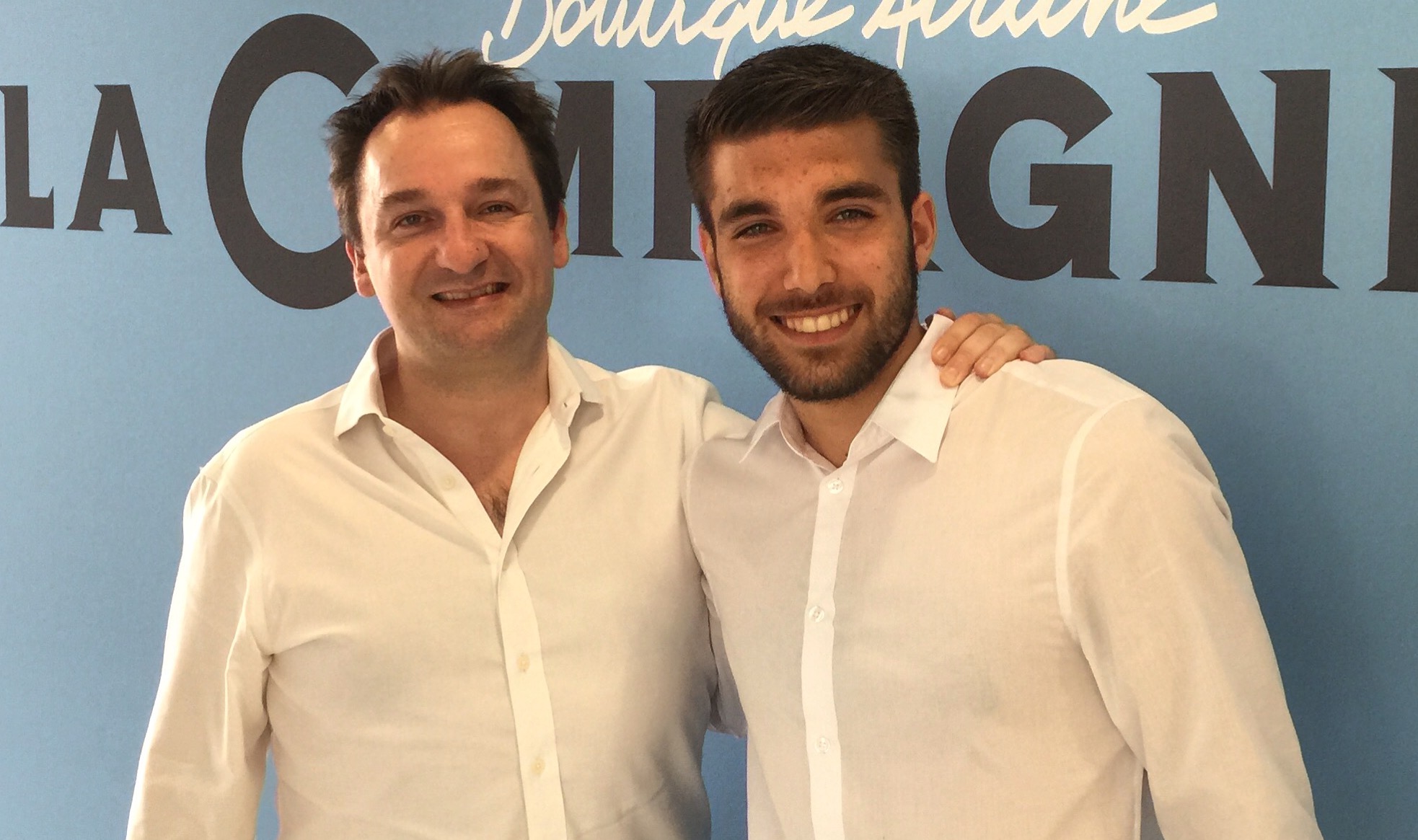 Two men standing together in front of a La Compagnie backdrop.