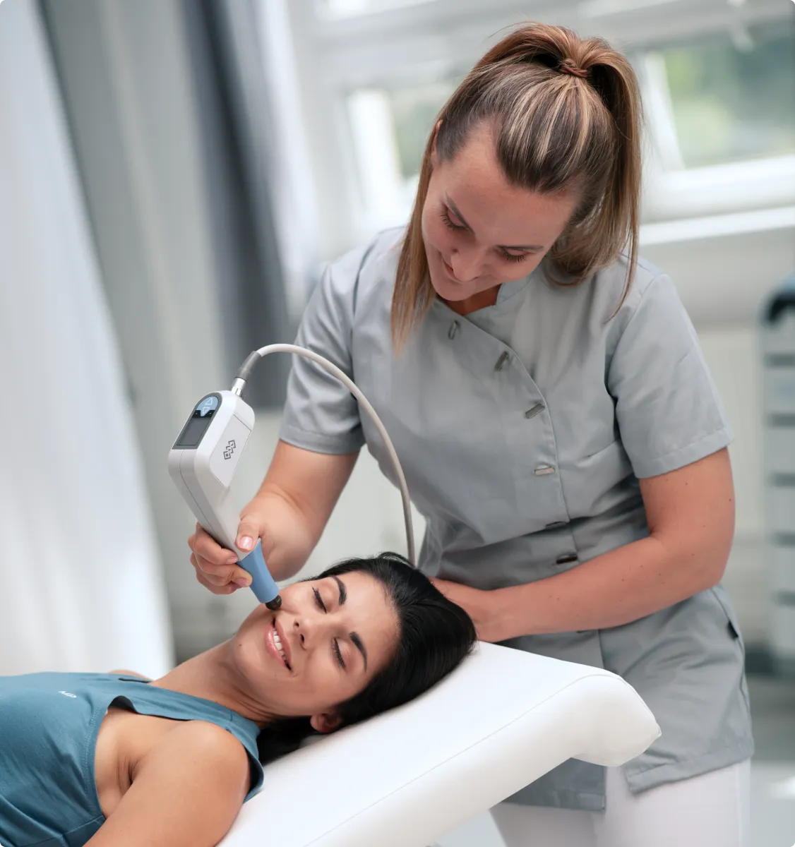 Kliniker använder BTL-enhet för estetisk behandling på patientens ansikte och käkkontur.
