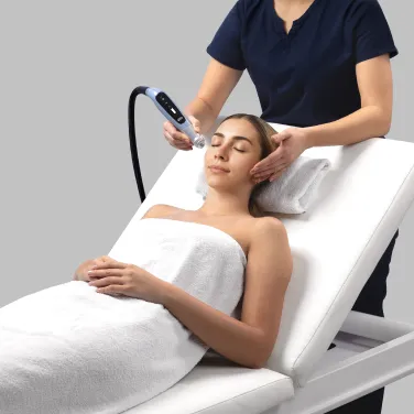 Behandlare applicerar BTL EMFUSION-behandling på patientens ansikte för att stärka hudbarriären (hudbarriär).