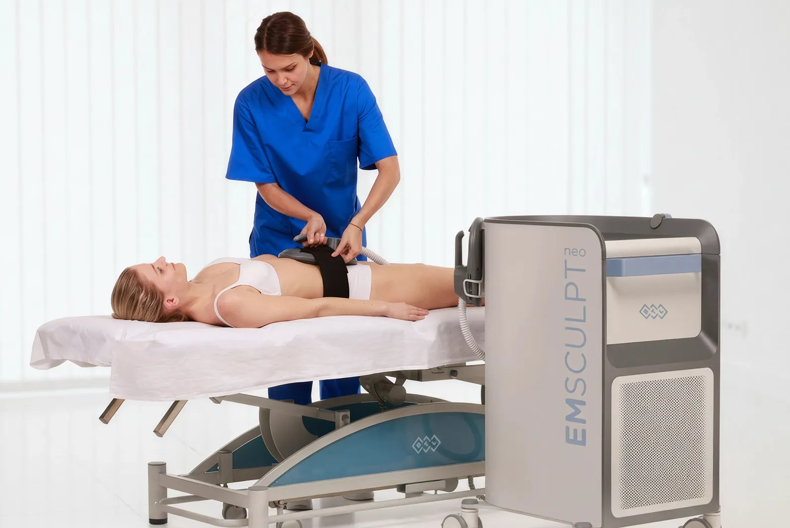 Patient genomgår BTL EMSCULPT NEO-behandling för kroppsformning på magregionen medan behandlare applicerar enheten.