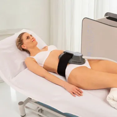 Patient ligger på behandlingsbänk med BTL EMSCULPT NEO-applikator placerad på buken för kroppsformning.