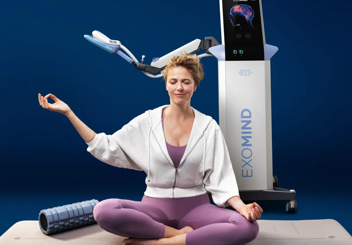Kvinna i meditativ yoga-position demonstrerar BTL EXOMIND hjärnstimulering med behandlingsenhet monterad på armen.