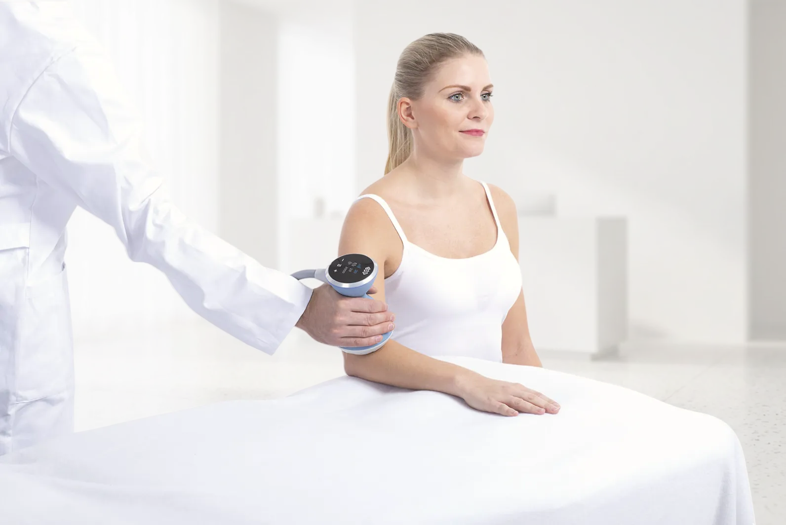 Sjukvardspersonal applicerar BTL Focused Shockwave-handapplikator på patientens arm under stötvågsterapi-behandling.