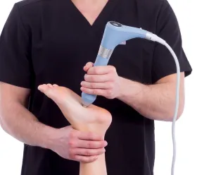Kliniker håller en BTL radiell stötvåg-applikator mot patientens biceps under behandling.