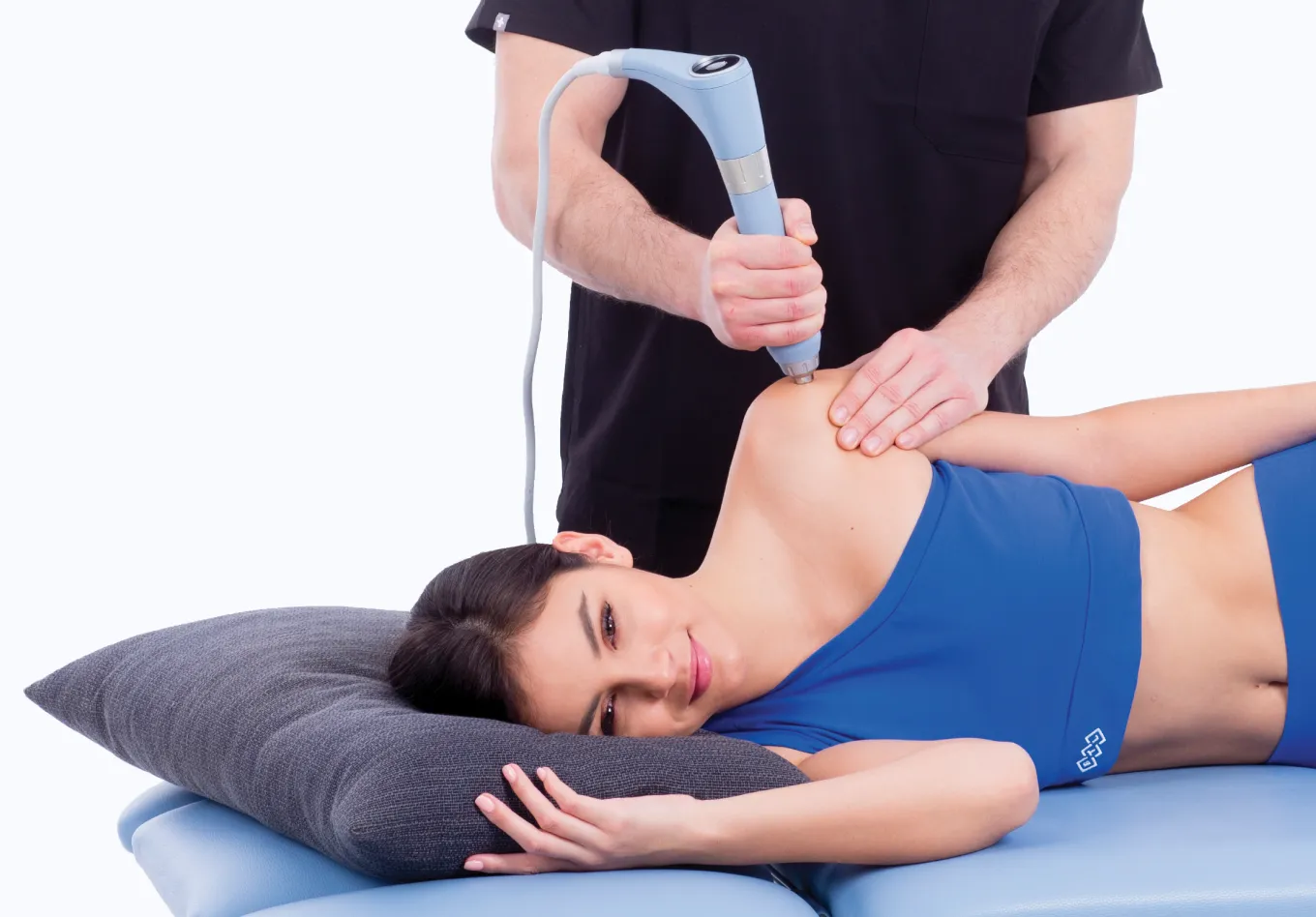 Patient ligger ned medan kliniker applicerar BTL radiell stötvåg på skuldra med Magnum-applikator.