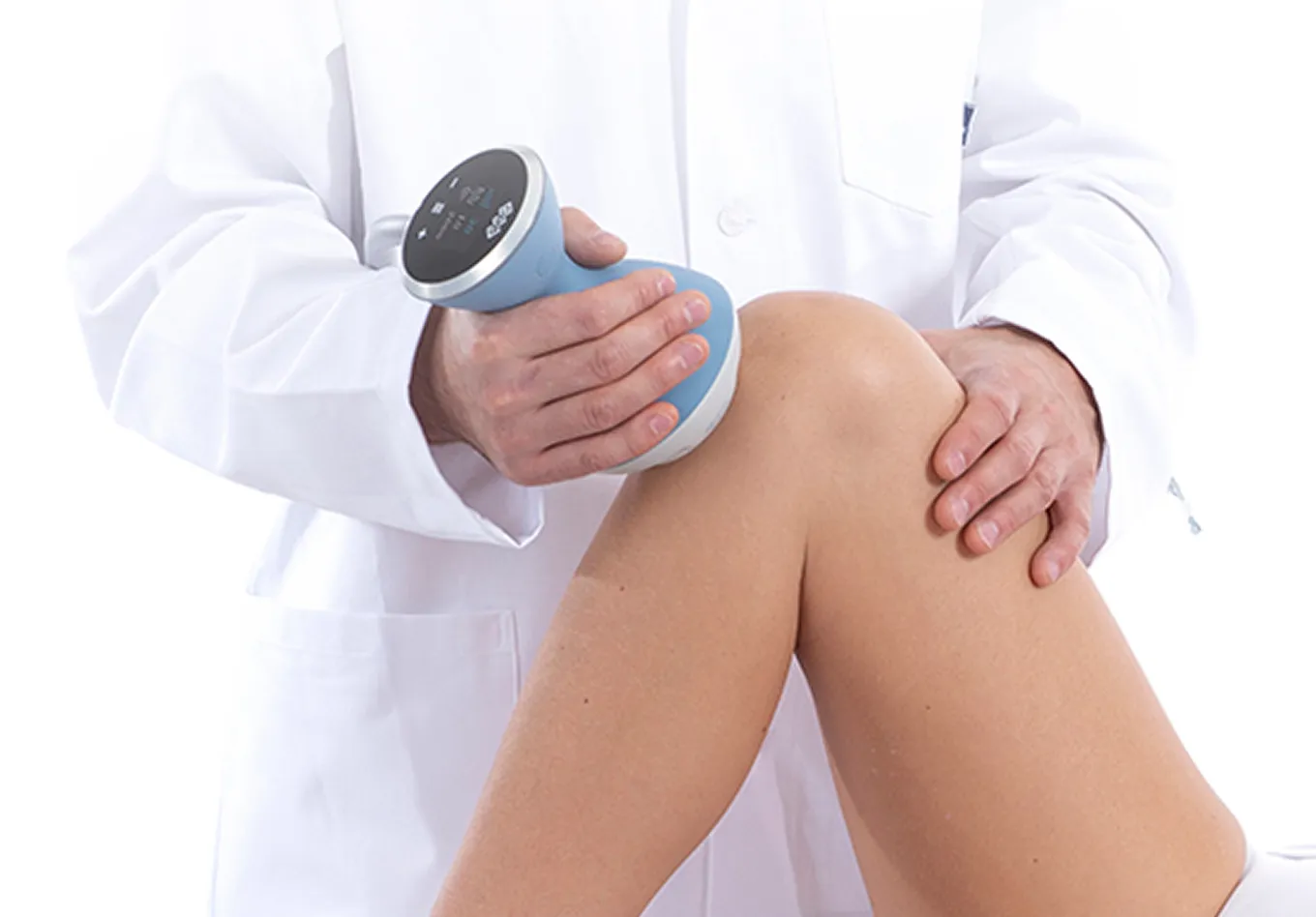 Medical professional in white coat using a blue handheld device on a patient's bent knee.