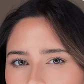 Close-up of a woman's eyes and eyebrows with dark hair framing her face.