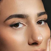 Close-up of a woman's face showing smooth skin, brown eyes, and well-groomed eyebrows.