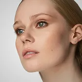 Close-up of a woman's face with clear skin and light makeup looking slightly upwards.