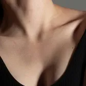 Close-up of a woman's neck and upper chest area in a black top.