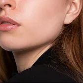 Close-up of a woman's jawline and lips with smooth skin and light makeup.