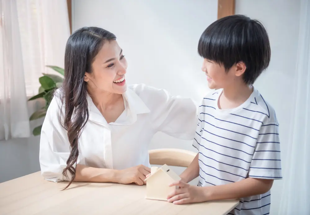 Smiling Asian woman looking warmly at a young boy seated at a table, representing one-on-one coaching at SuperMinds Singapore.