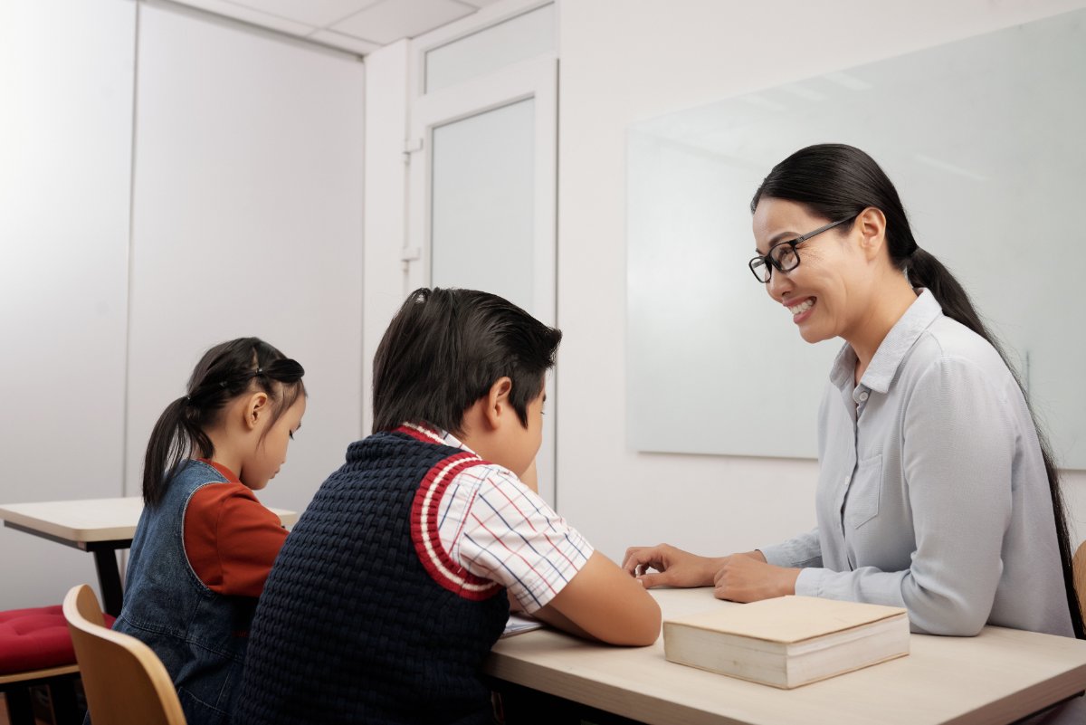 Small group of Singaporean primary school children in a public speaking class, listening attentively