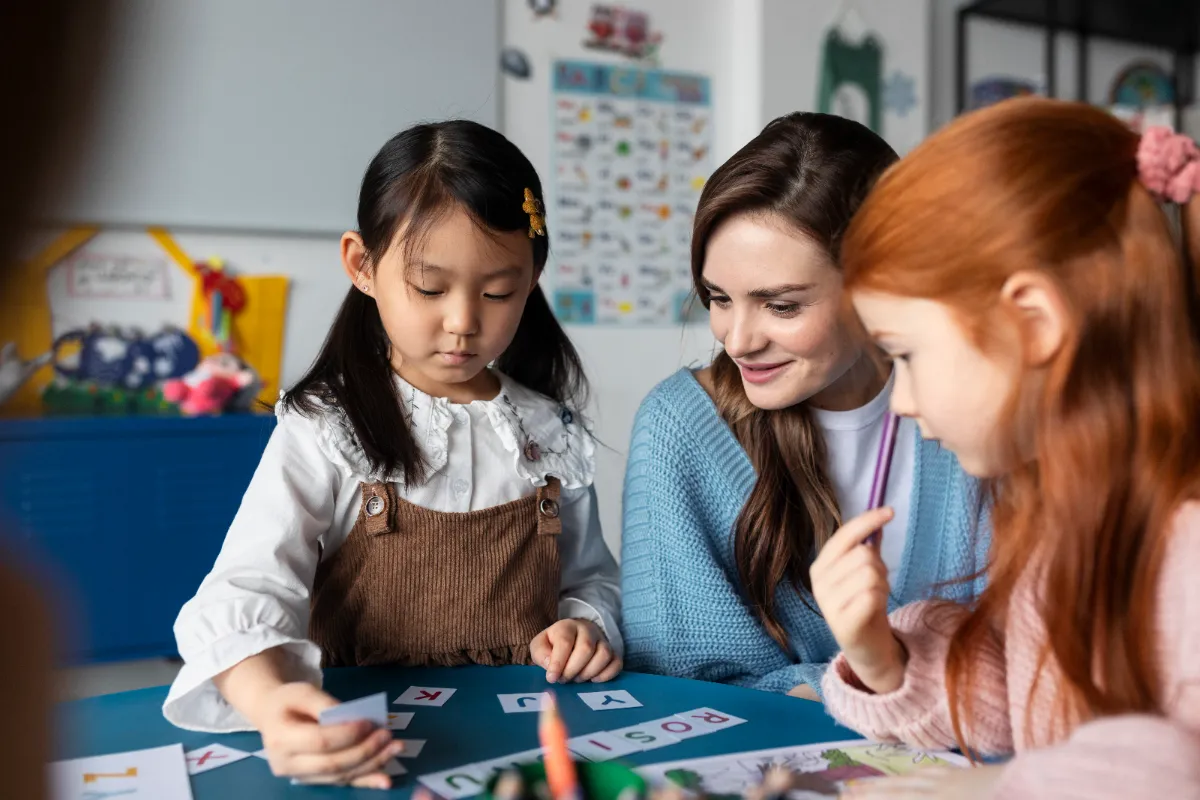 Asian children and teacher in a small group table discussion, students engaged in conversation and listening attentively