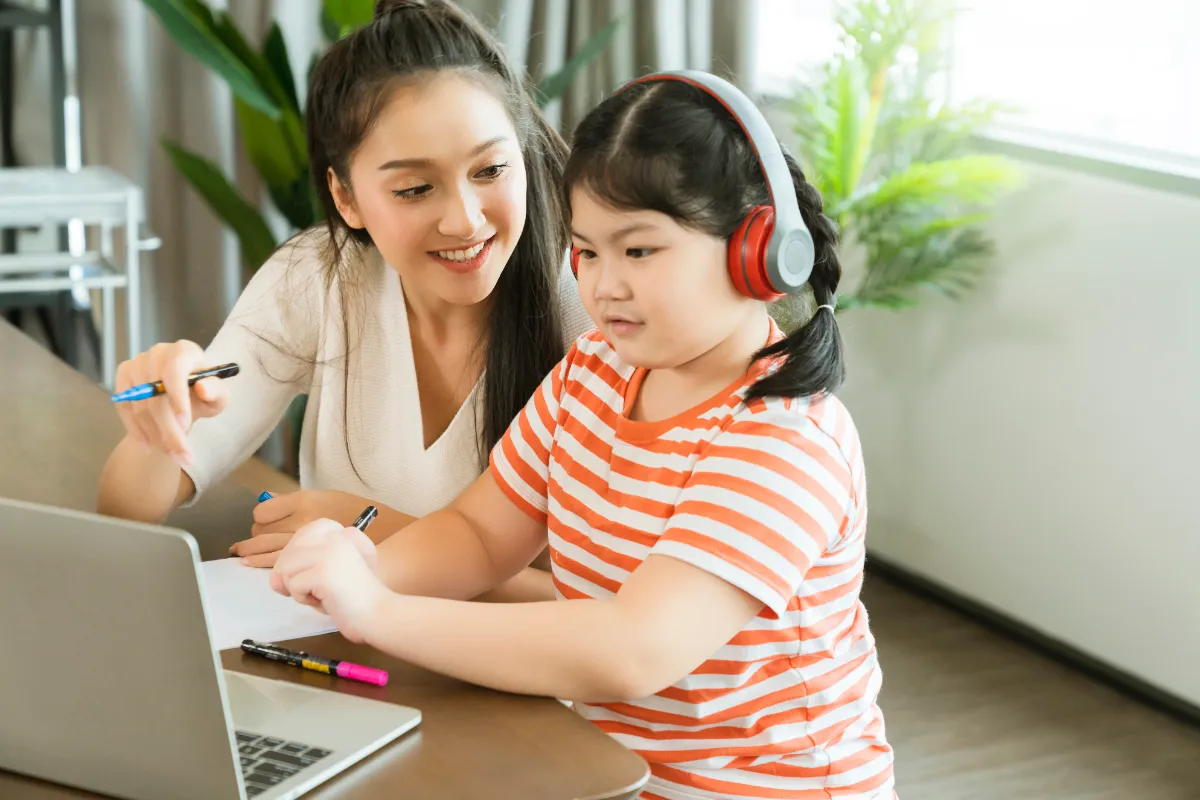 Asian mother sitting with her daughter at home in the evening, helping her prepare and study for the DSA interview